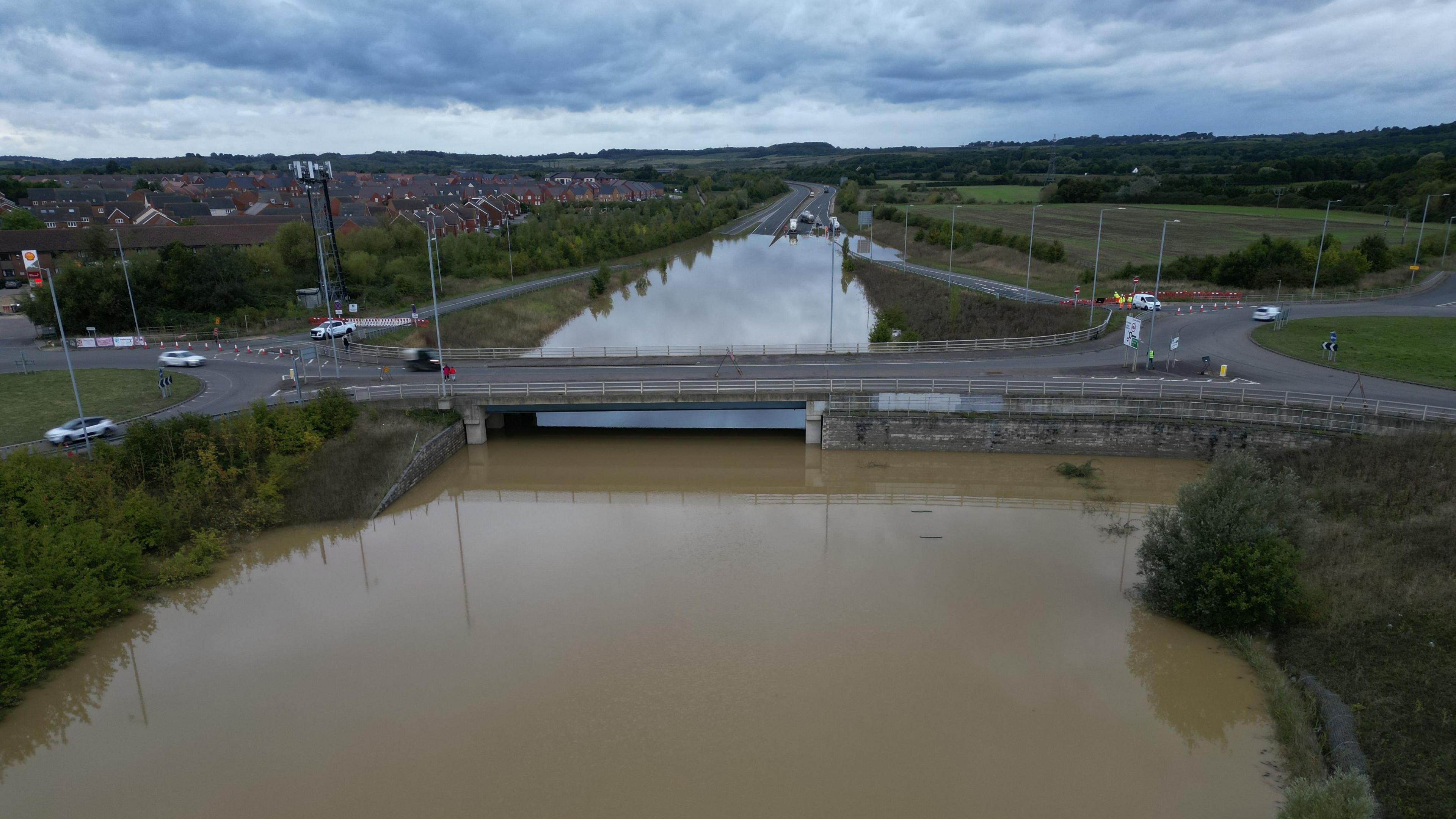 Murky brown water has submerged a road affected by heavy rainfall. 