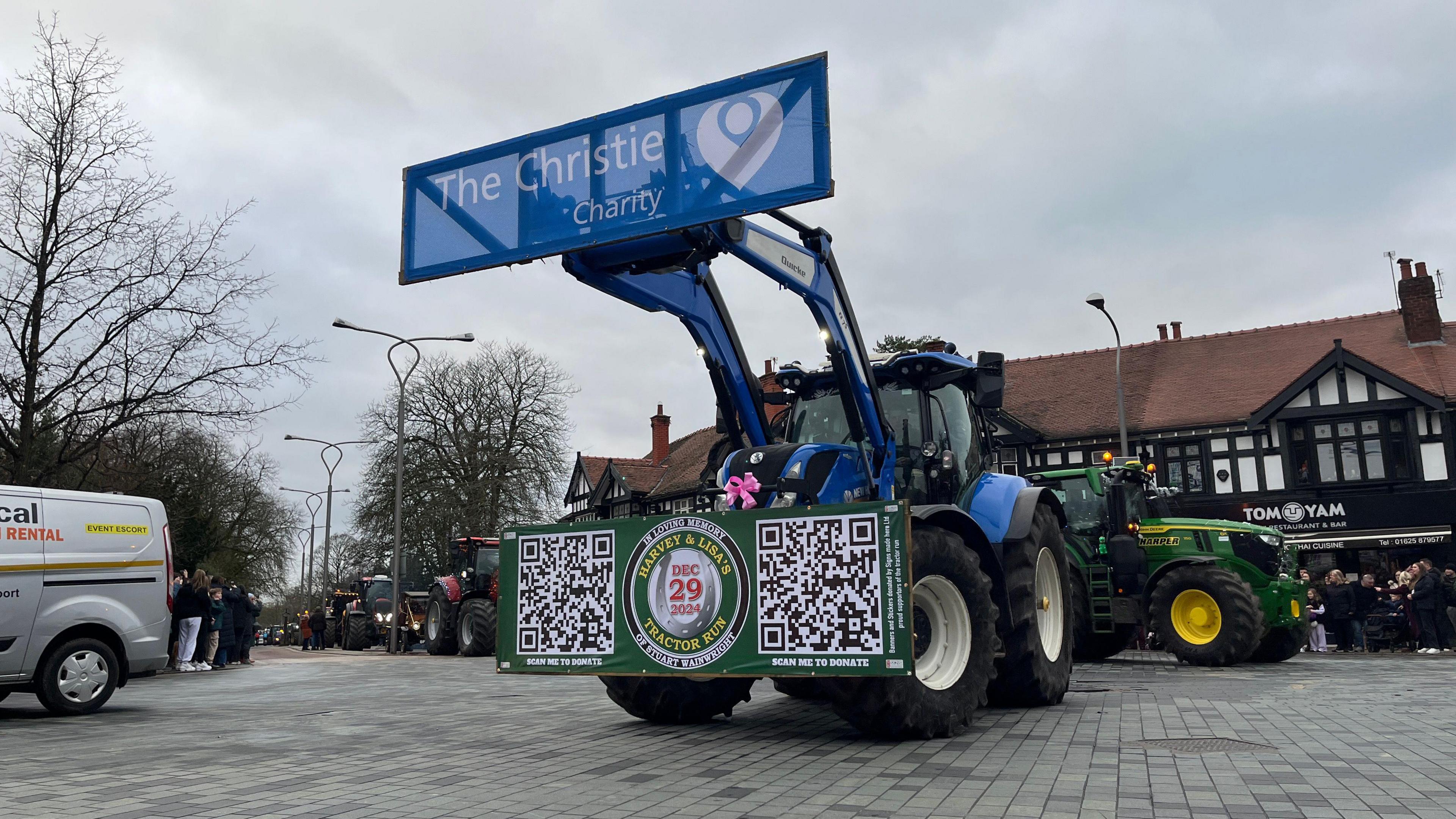 A large blue tractor with a sign saying The Christie Charity, in a town square.