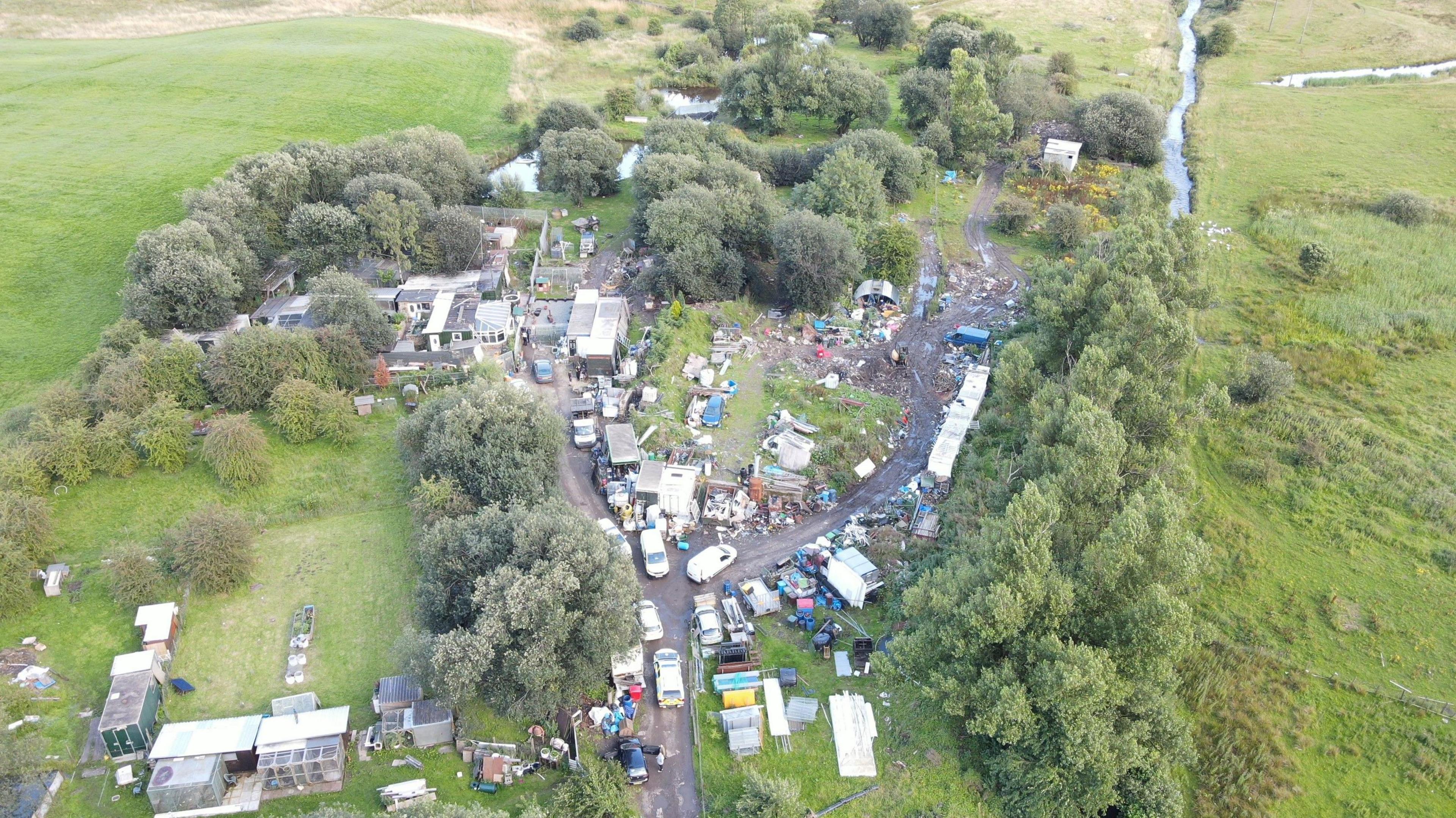 A drone shot of Dearden's home compound in a large plot of land with several containers, buildings and outbuildings in countryside.