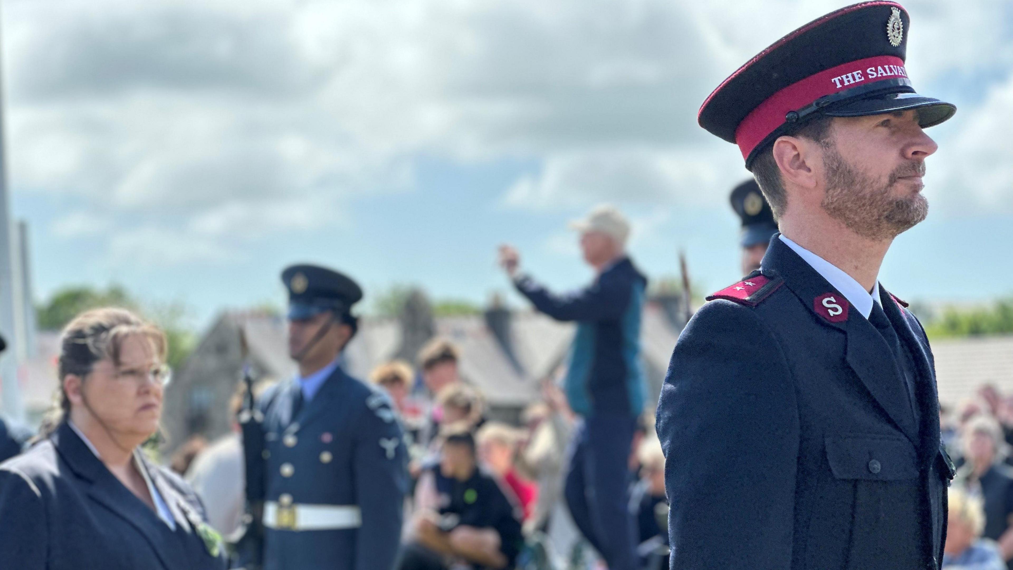 Captain Dylan Nieuwoudt of the Salvation Army in uniform with crowds behind him.