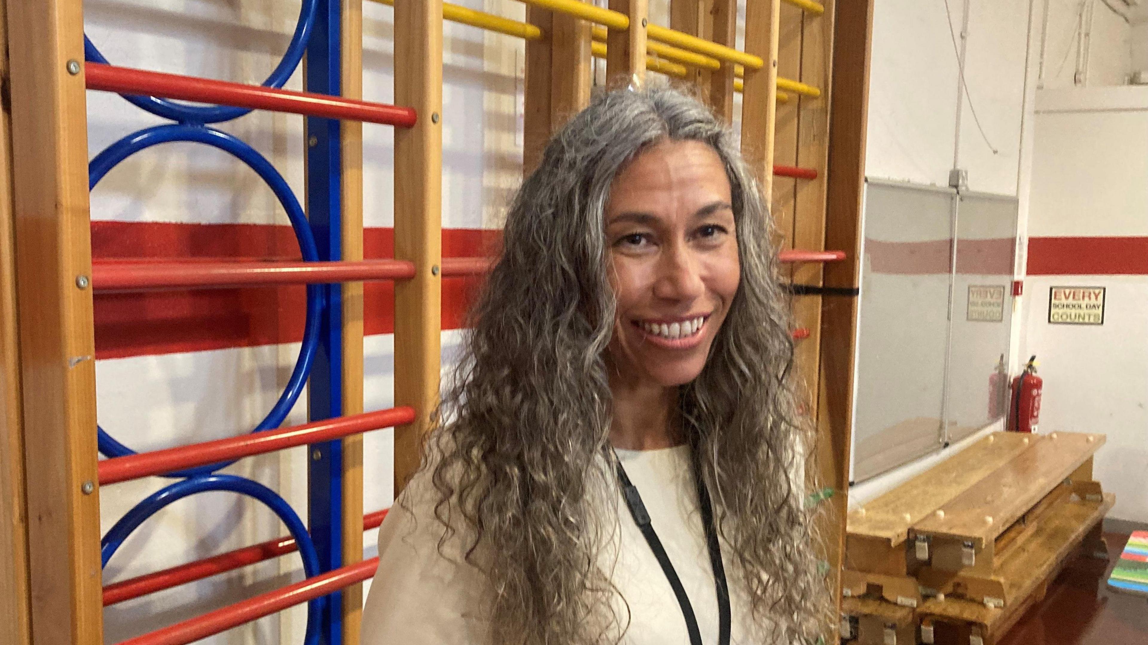 Head teacher Terri Cheung is standing in a school gym. 