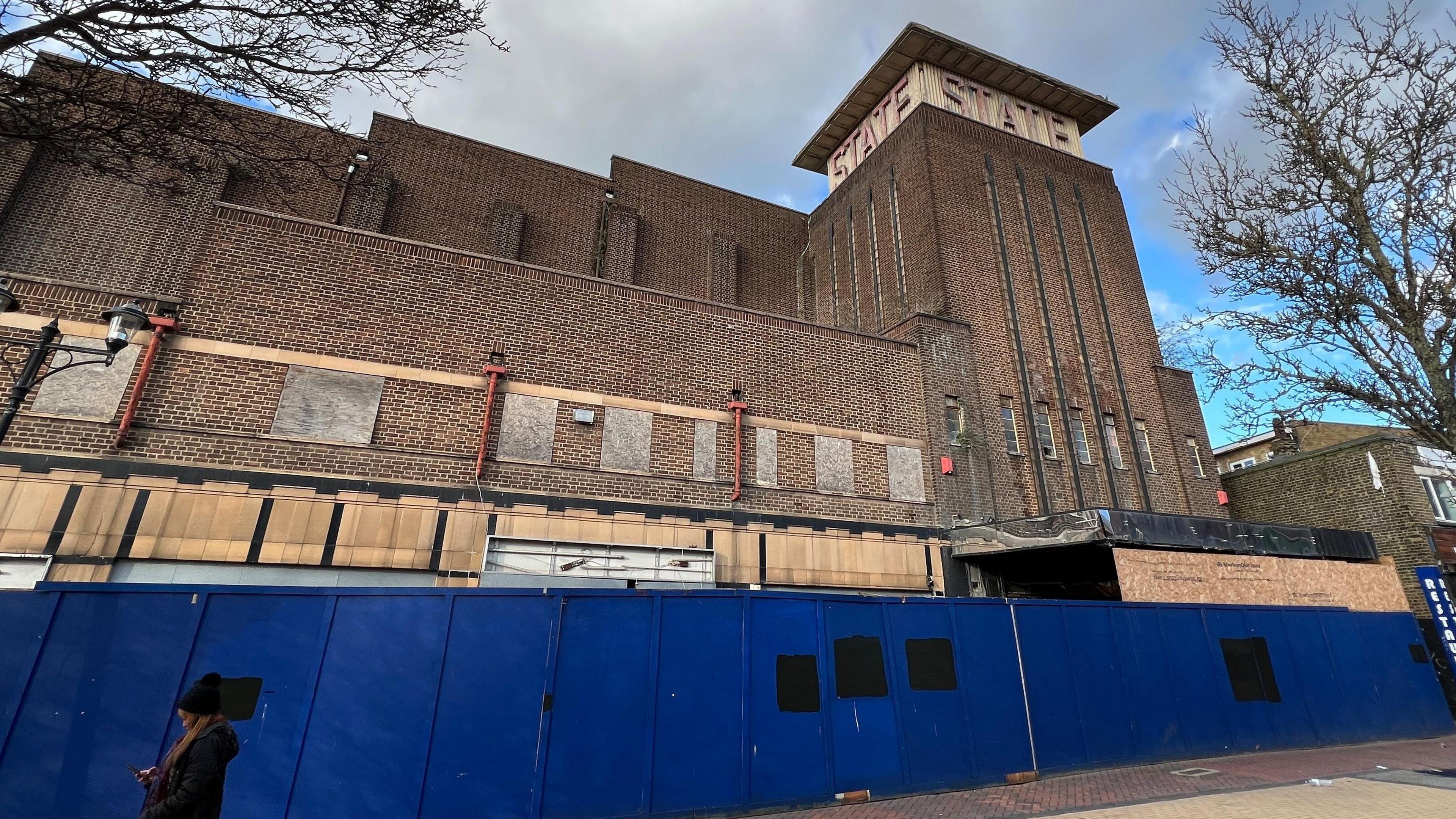 An old building boarded up with blue fencing