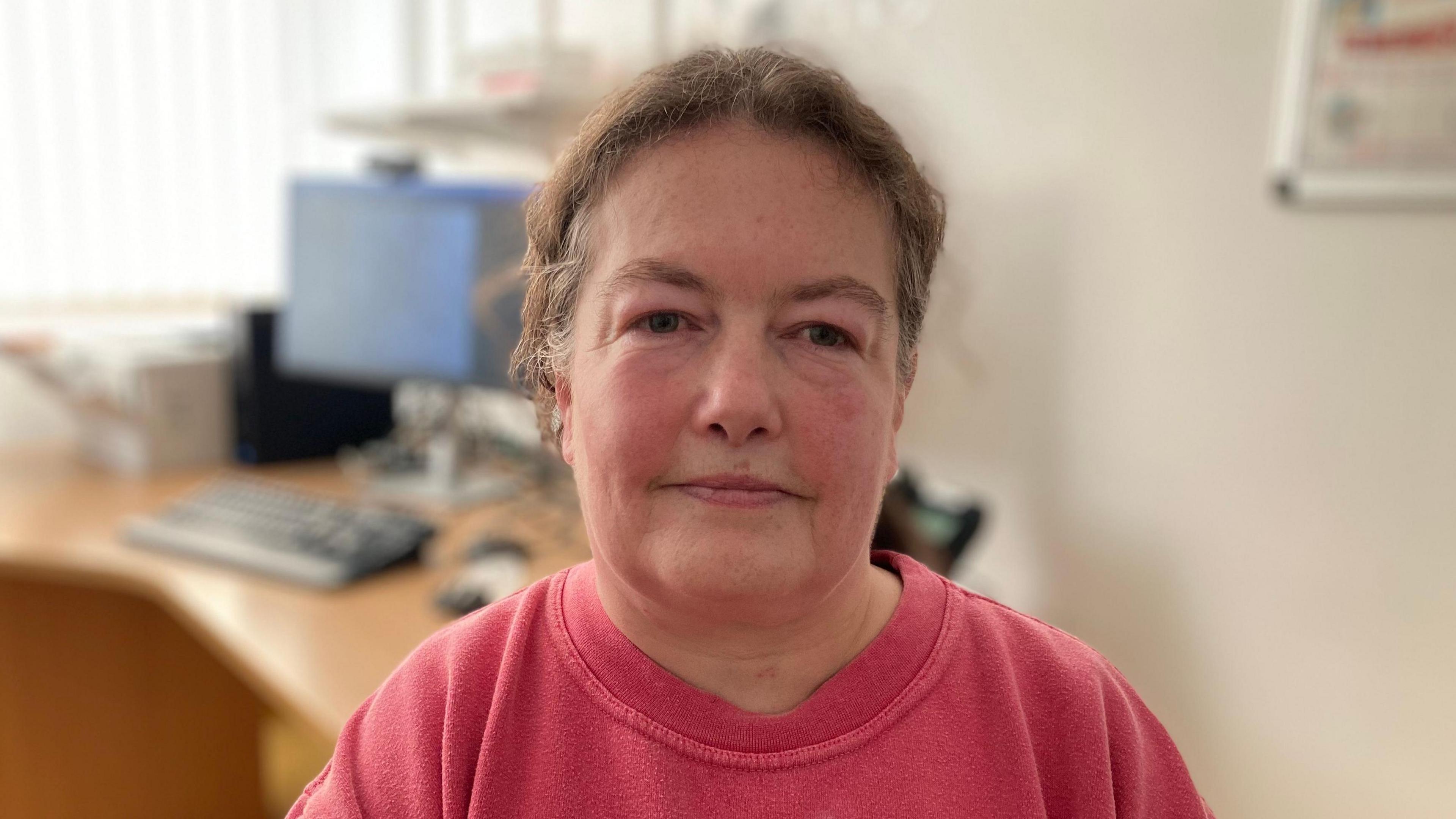 Heart patient Karen Cooper, aged 54  looks to the camera in a doctor's consultation room 