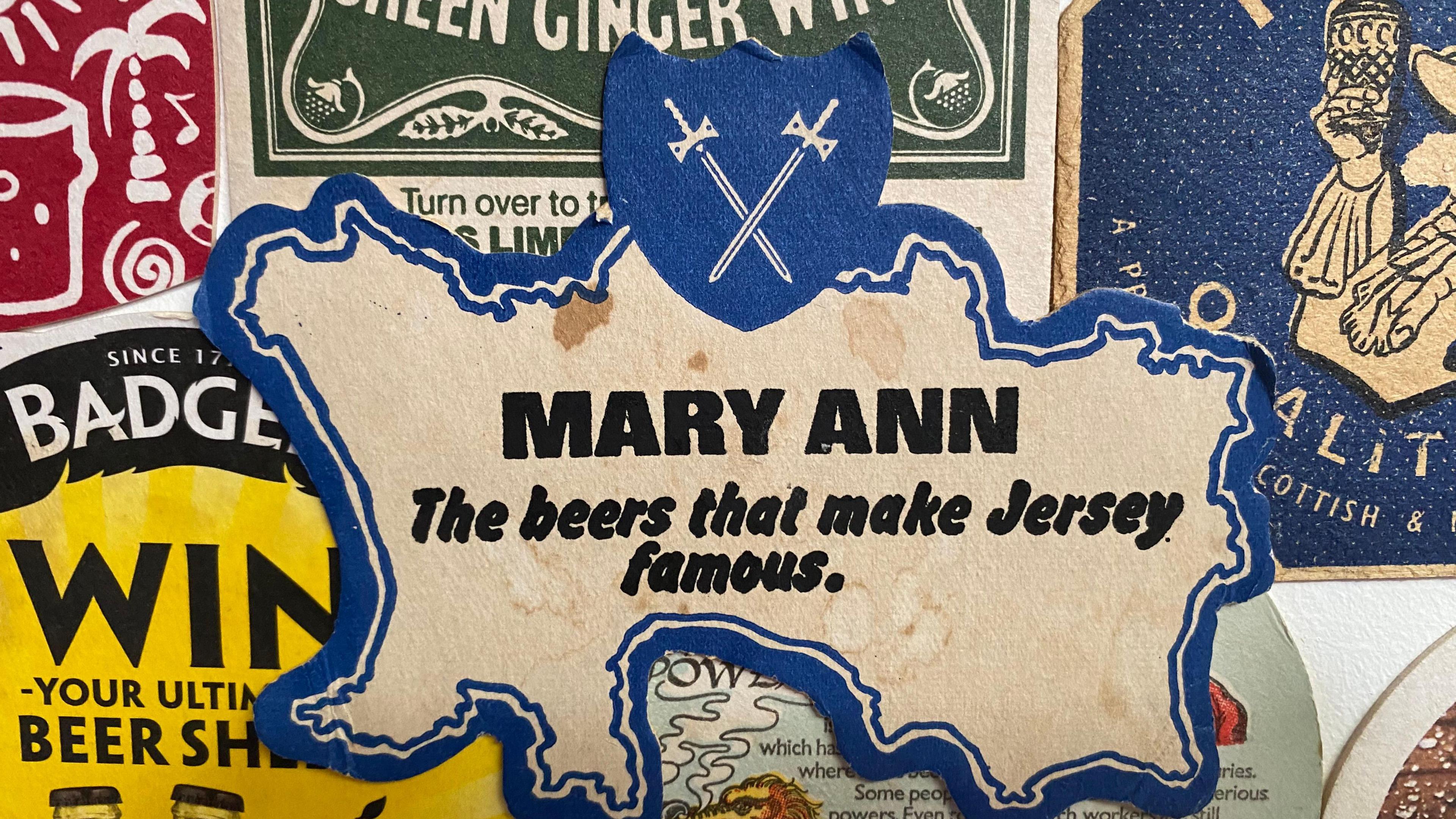 A beer mat shaped in the contours of the Channel Island Jersey, with text saying Mary Ann, followed by text saying The Beers that make Jersey famous.