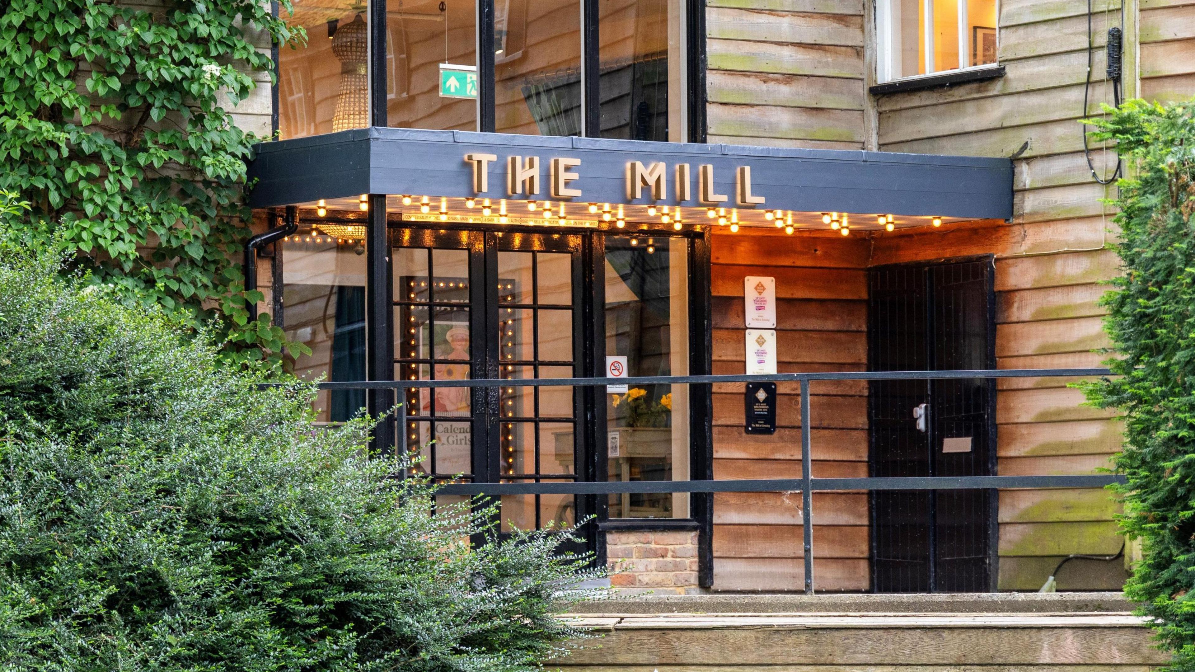 A general view picture of The Mill's foyer, which is clad in wood with lights on its roof and lettering that says "The Mill."