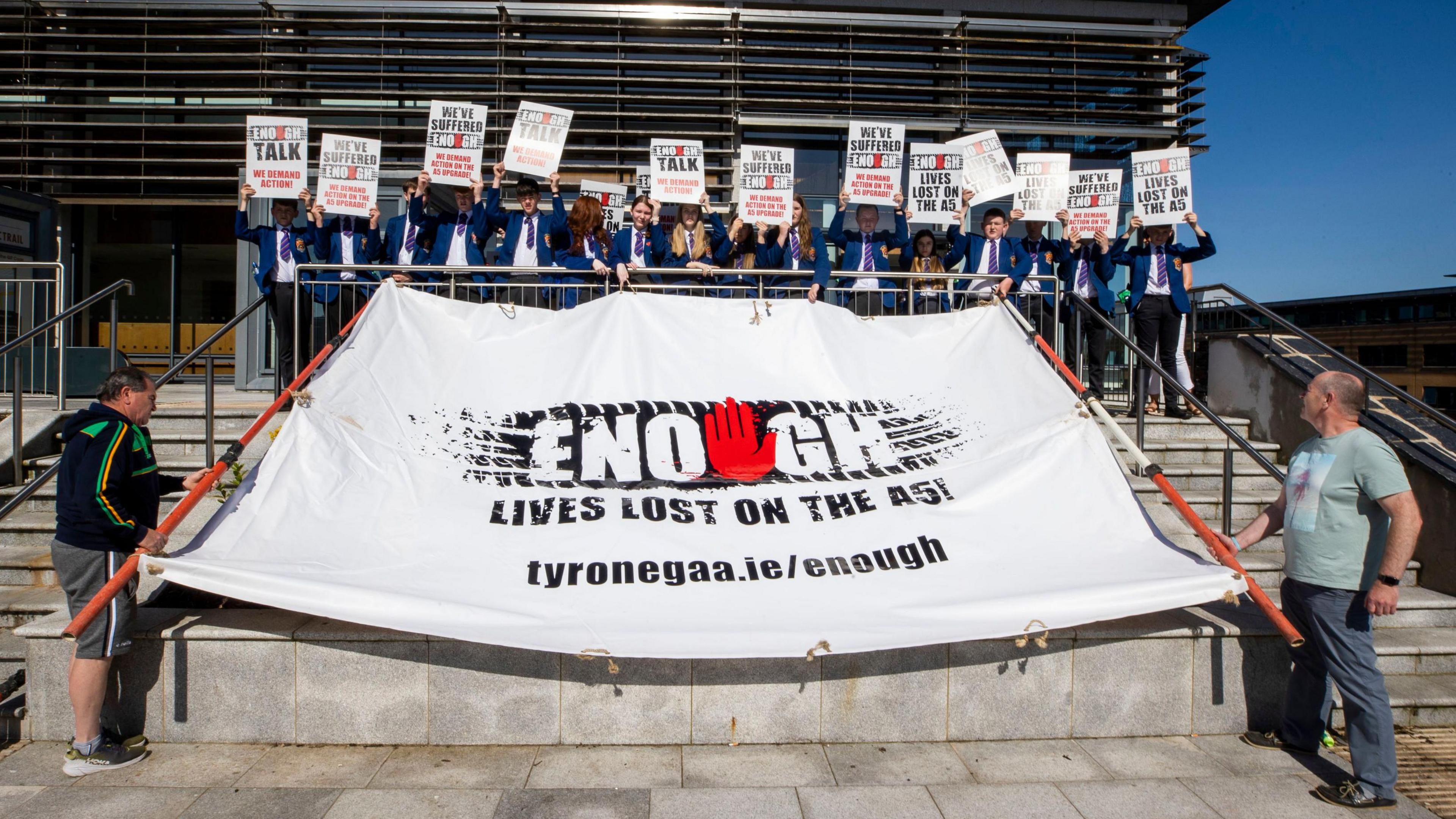 Students and staff from Sacred Heart College in Omagh, holding placards, with supporters of the Enough is Enough group in May 2023