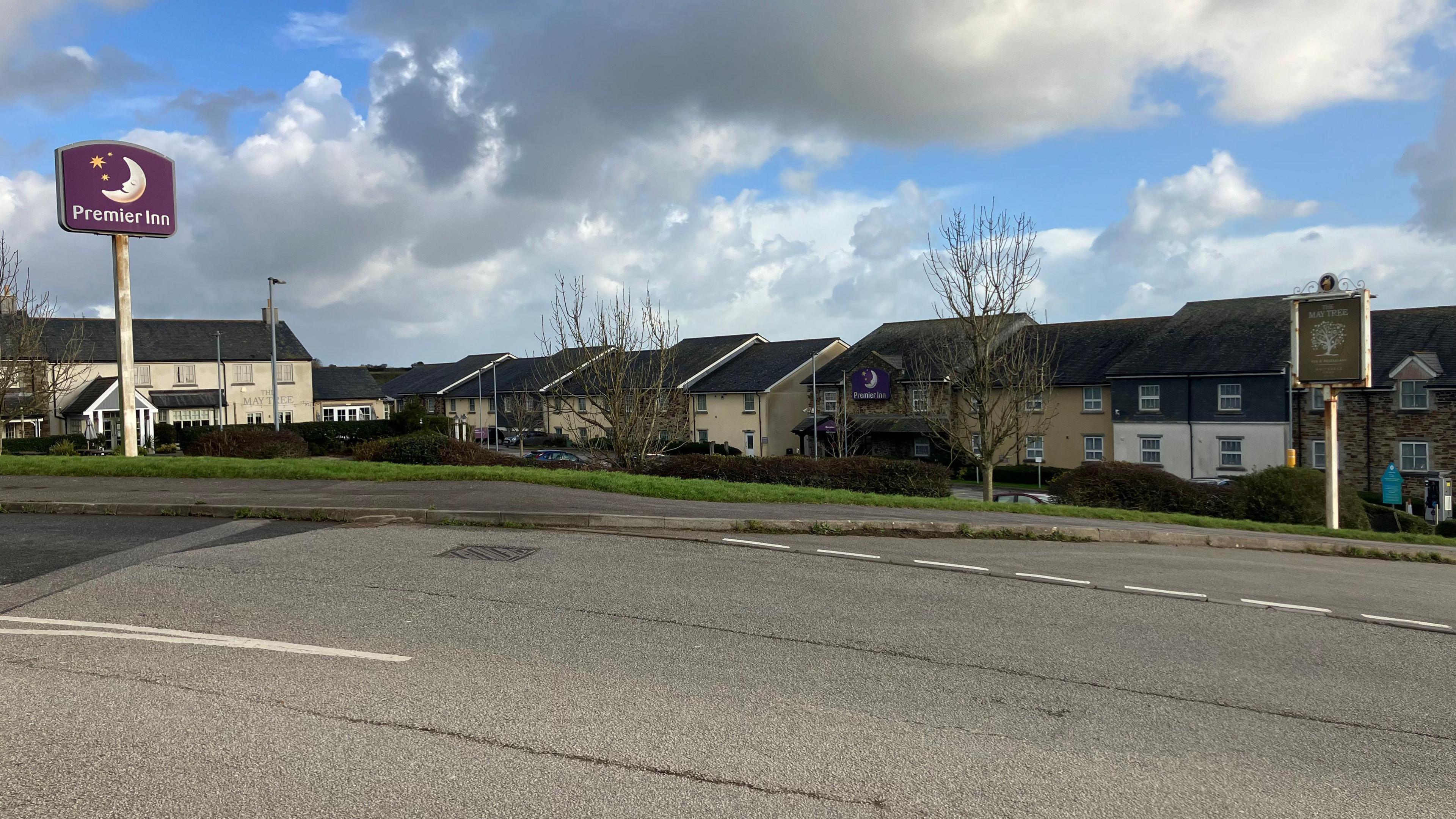 Clouds drift over a Premier Inn hotel and the May Tree pub in Helston. There are no cars on the road.