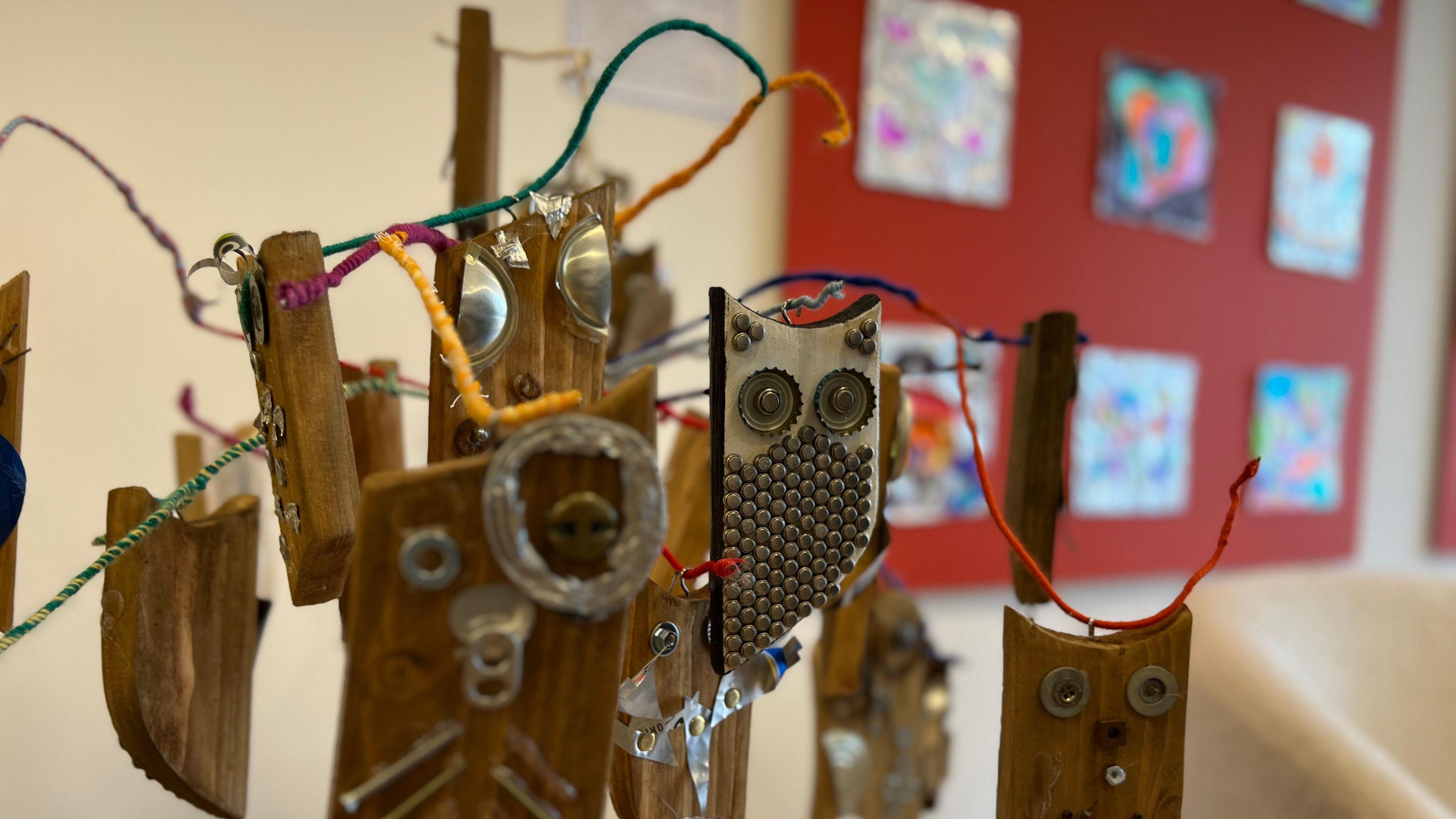 A modern art sculpture of a tree full of owls made out of various materials like wood, wire and bottle tops