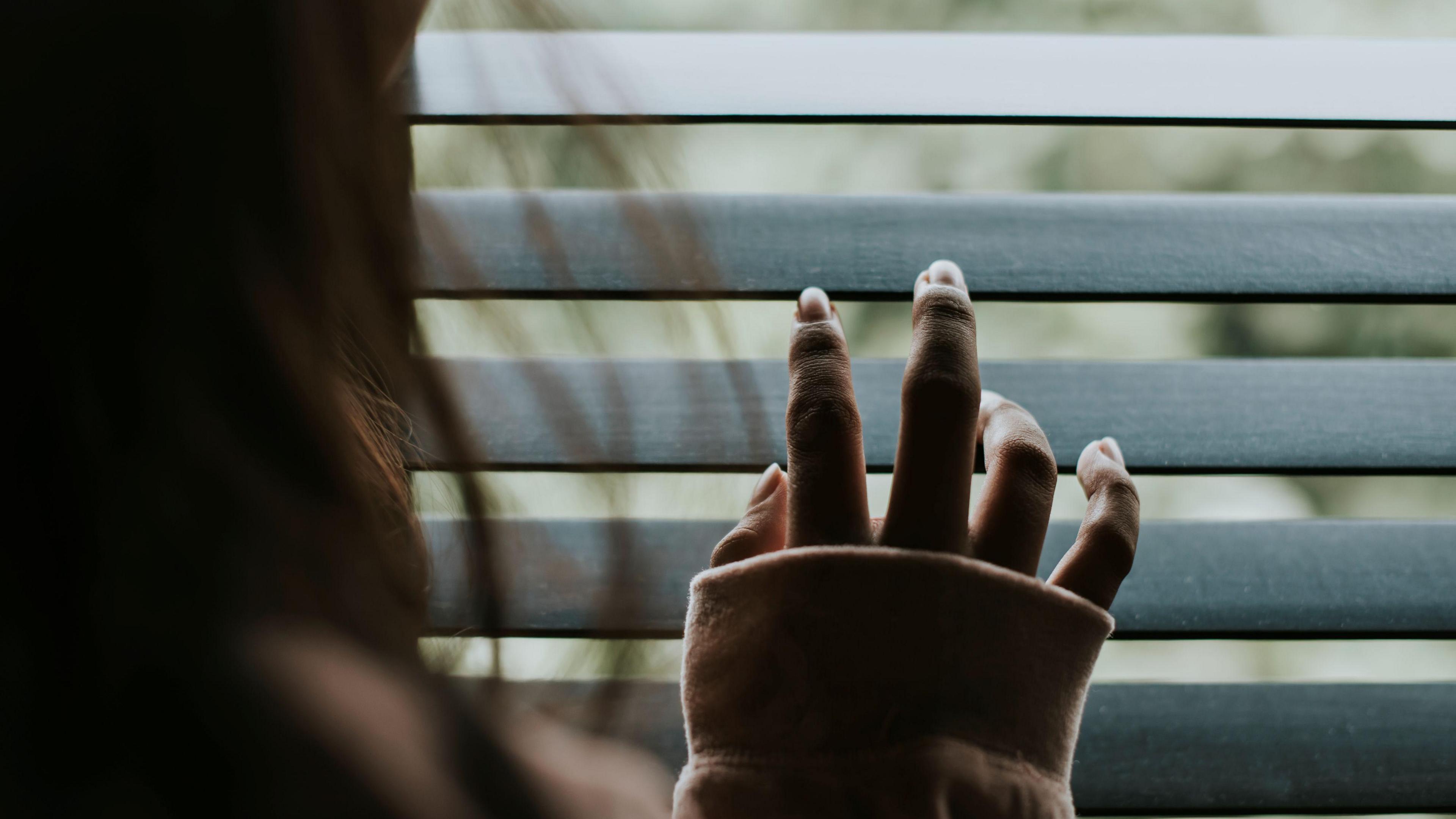 Woman looking out the window blinds