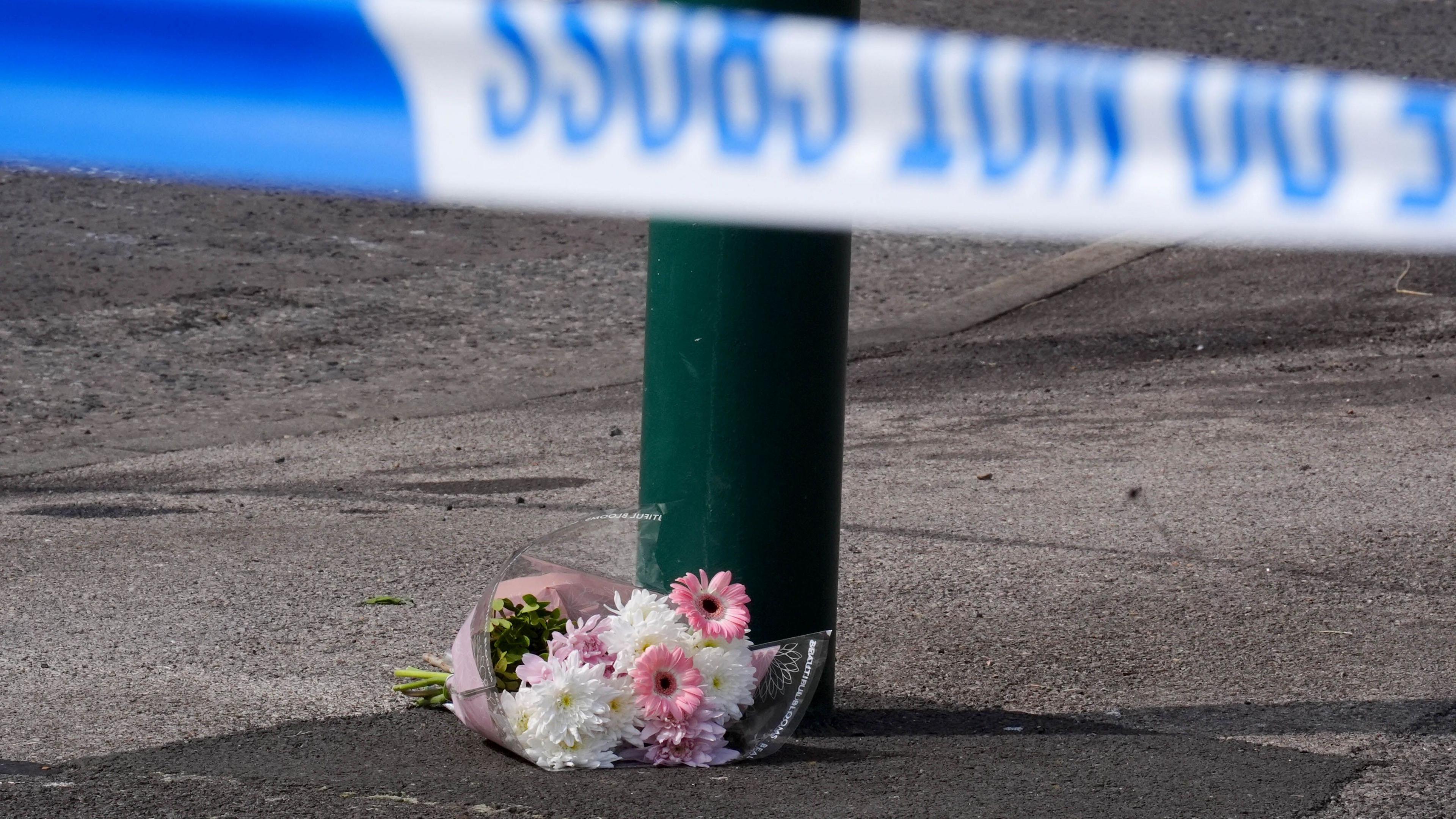 A floral tribute left near the scene, where a murder investigation has been launched after two people died in a house fire at a property in Grangetown, near Middlesbrough. A bouquet of pink and white flowers lies next to a lamppost, with a police tape in front of it