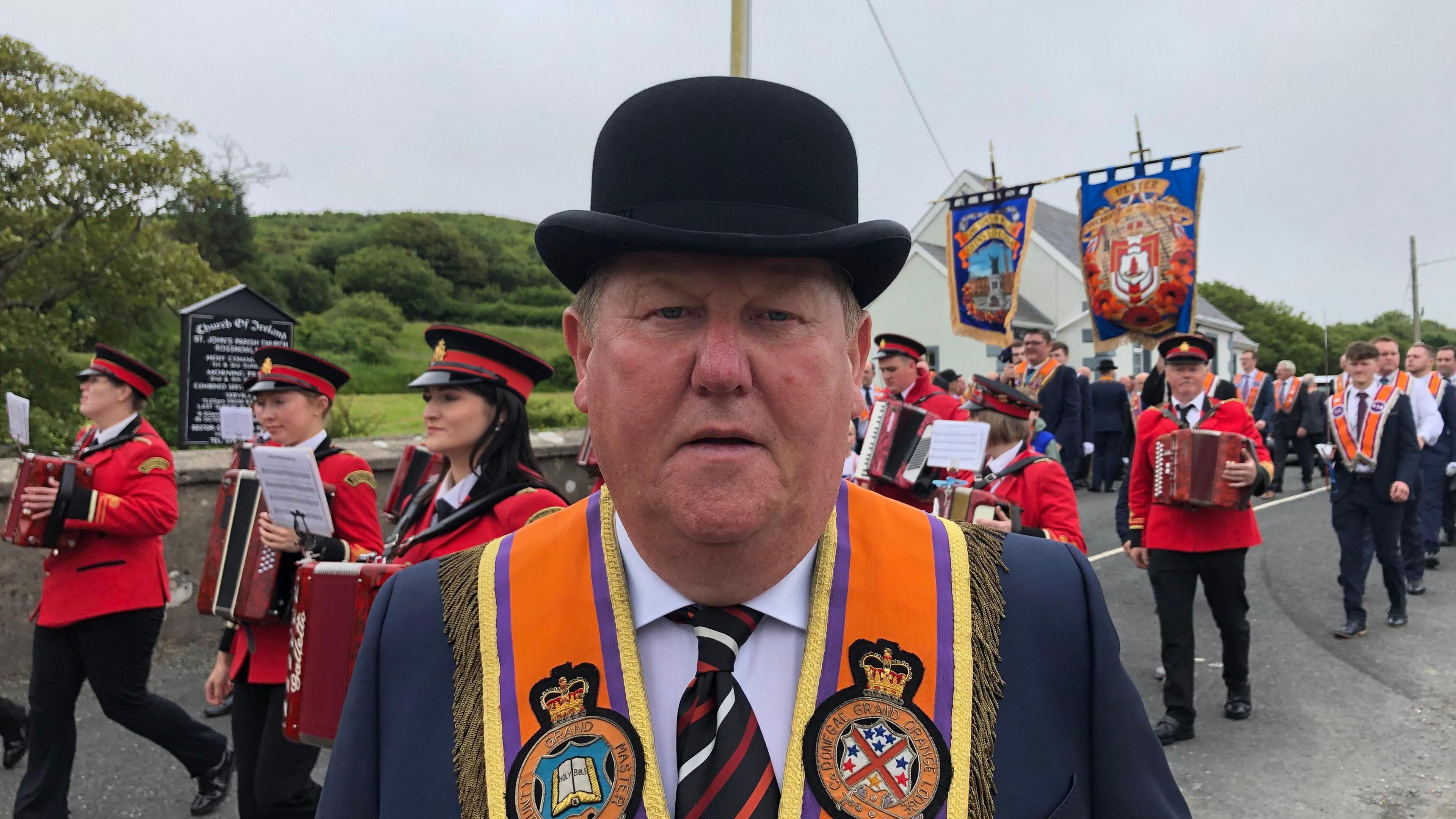 Donegal Grand Master David Mahon, centre of the photo, with an Orange Order parade walking behind him