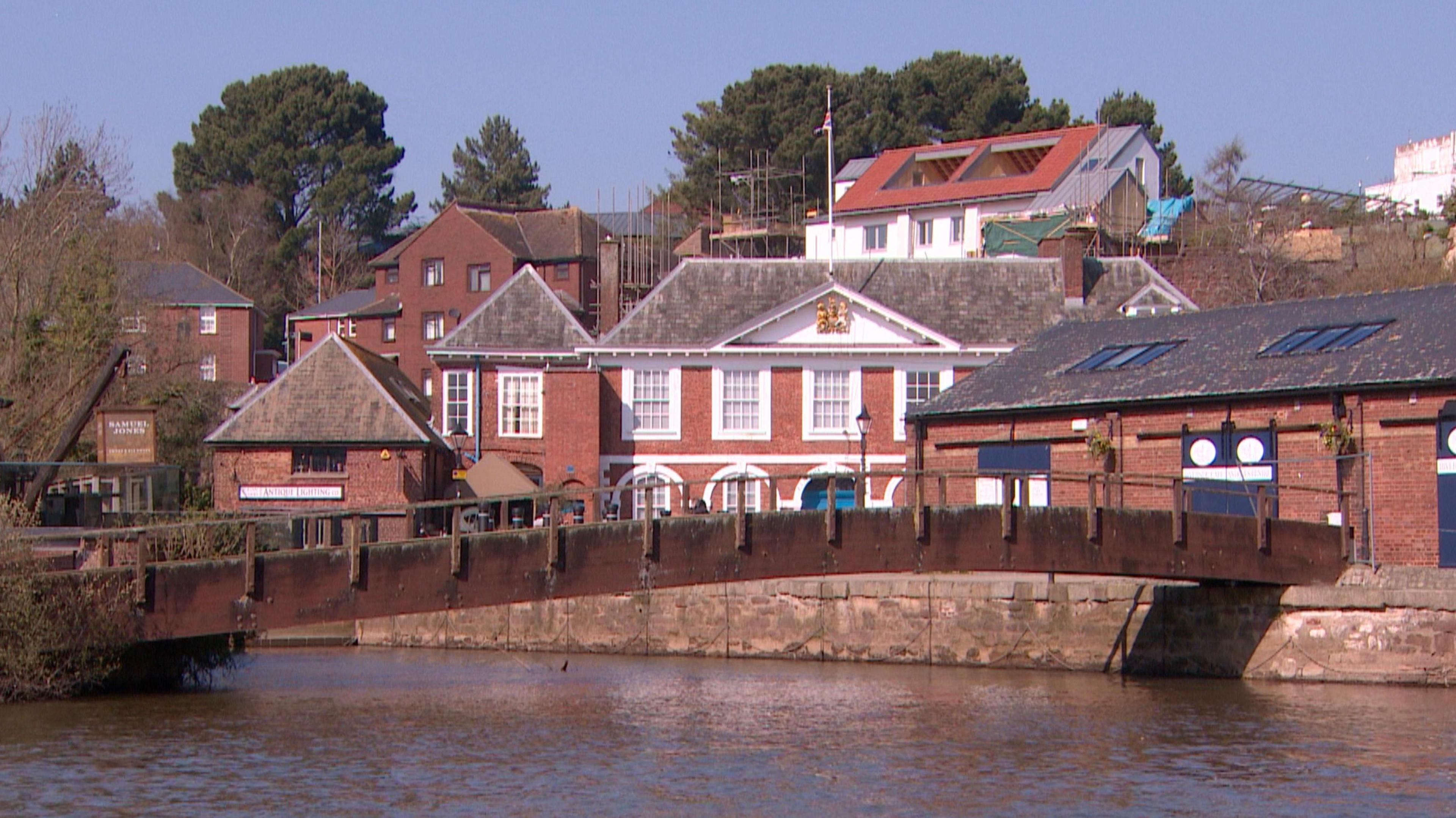 The wooden bridge over the water at Exeter quayside connecting two riverside walkways with Custom House in the background.