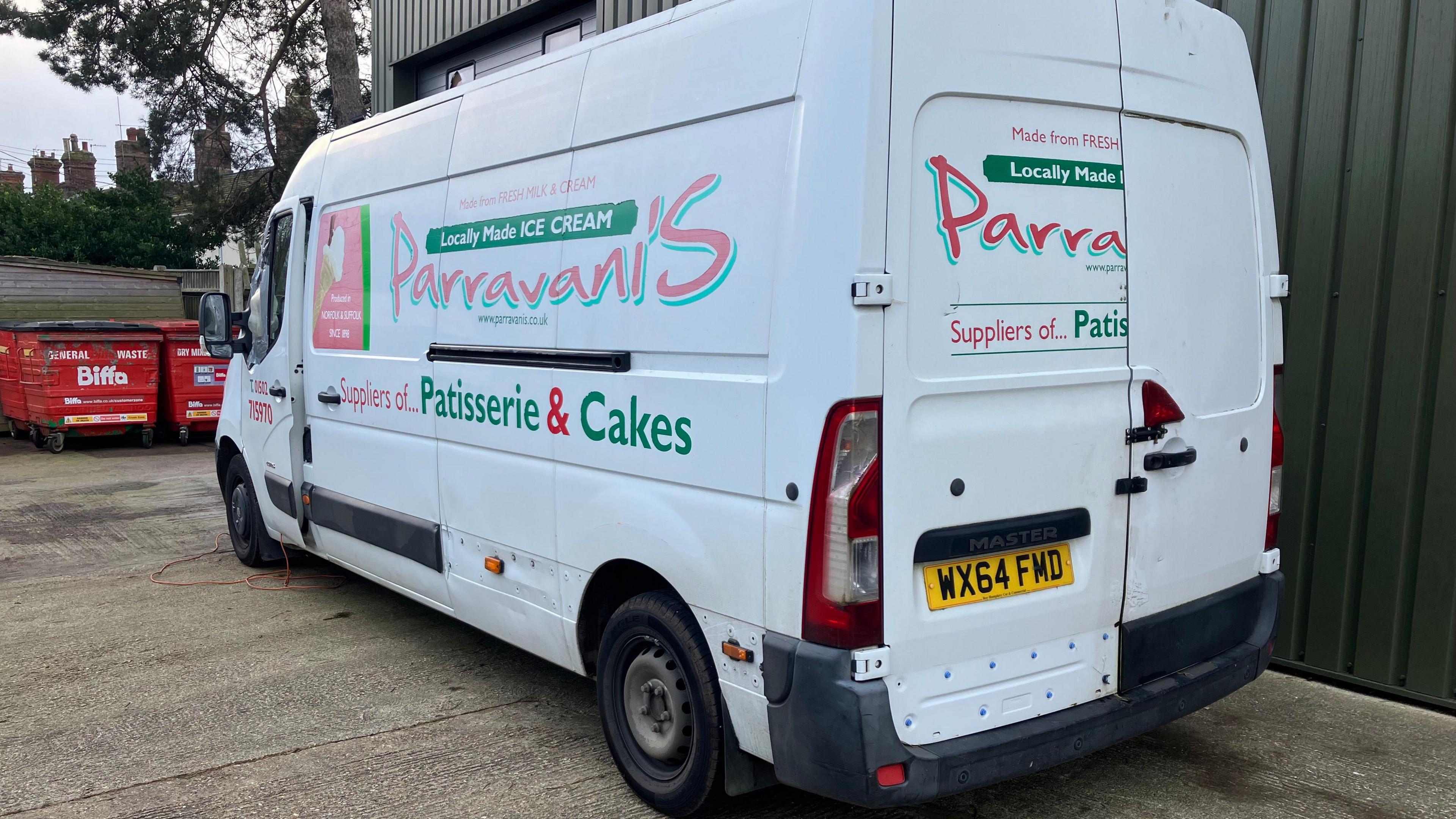 A large white van displaying the Parravani's logo is parked on concrete in the loading bay of the premises.