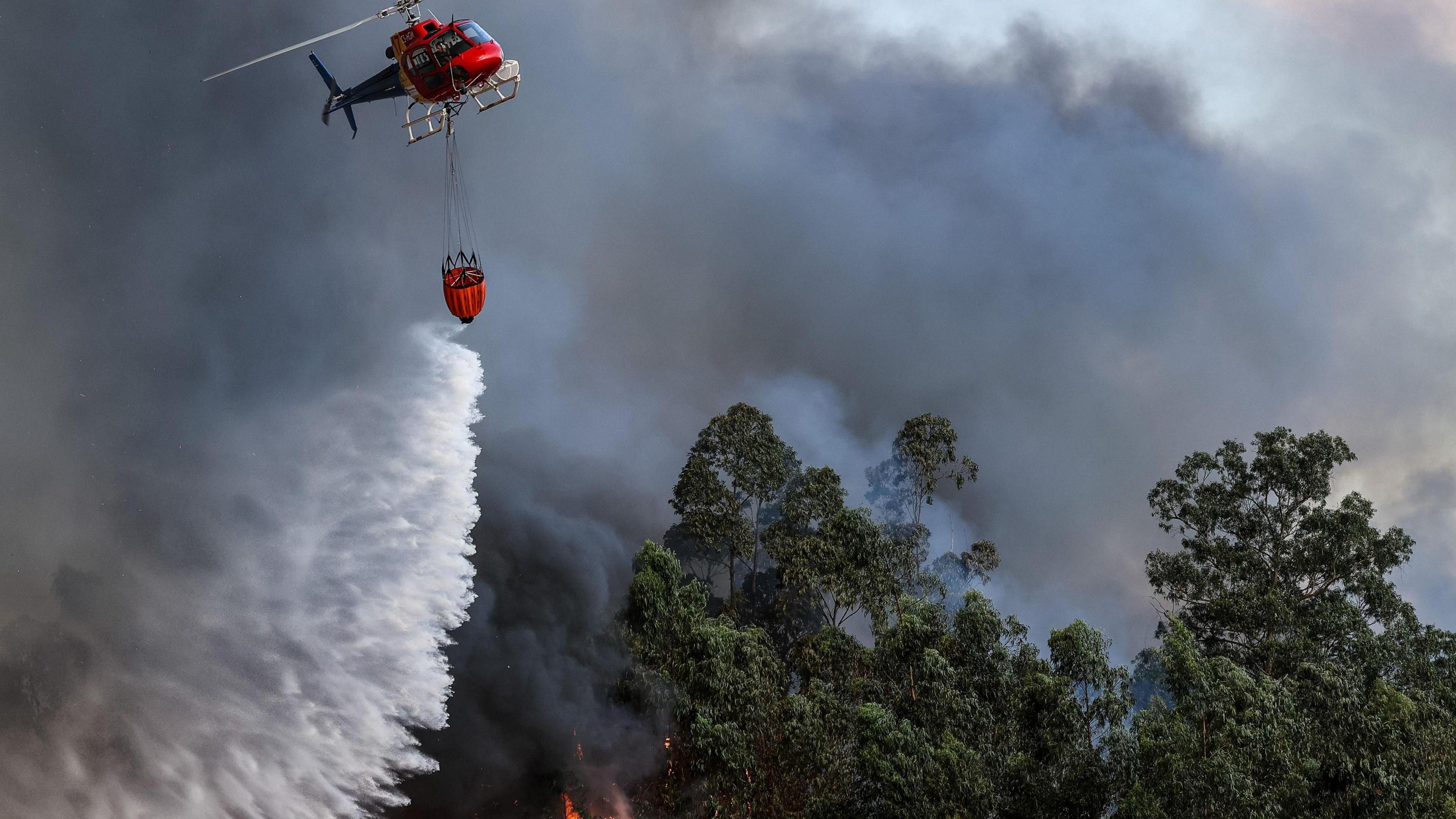 A helicopter drops water over a forest fire in Macinhata do Vouga, Albergaria-a-Velha, Portugal