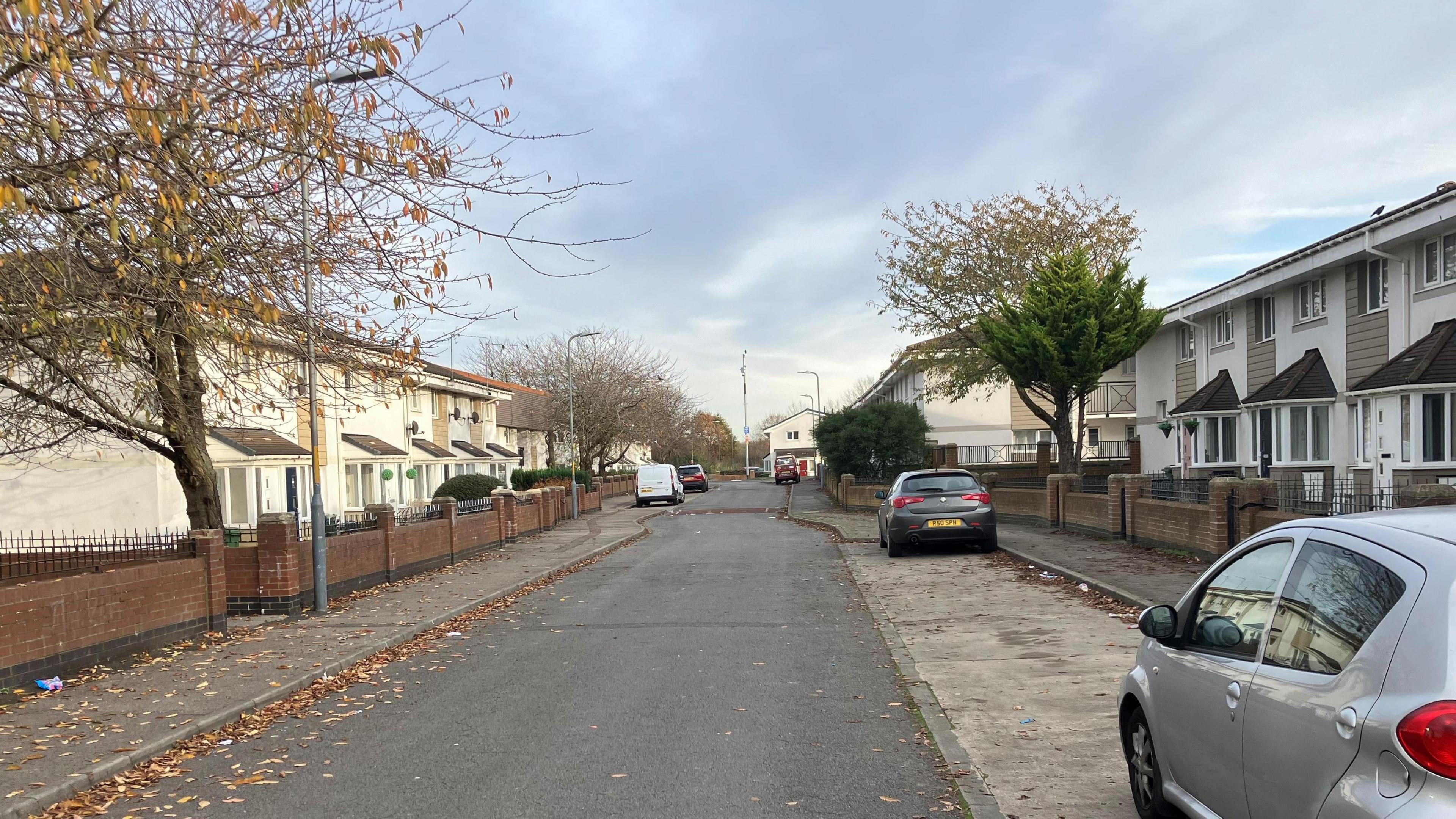 Kingston Road in Stockton. There are rows of white houses on each side of the street  and two parked cars on the right side. 