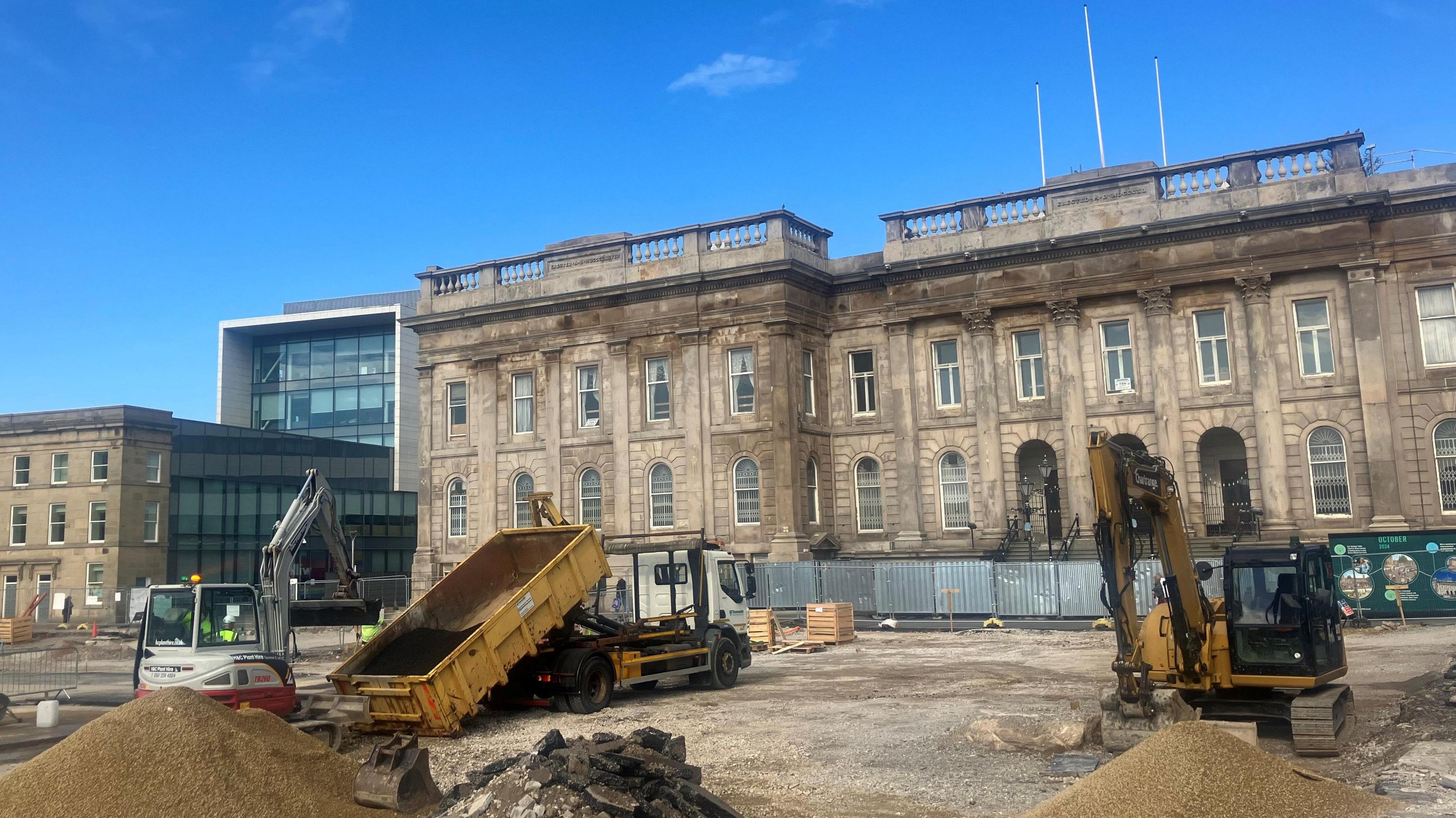 Photograph of Ashton Town Hall. In the foreground are diggers which are building the new outdoor market canopy.