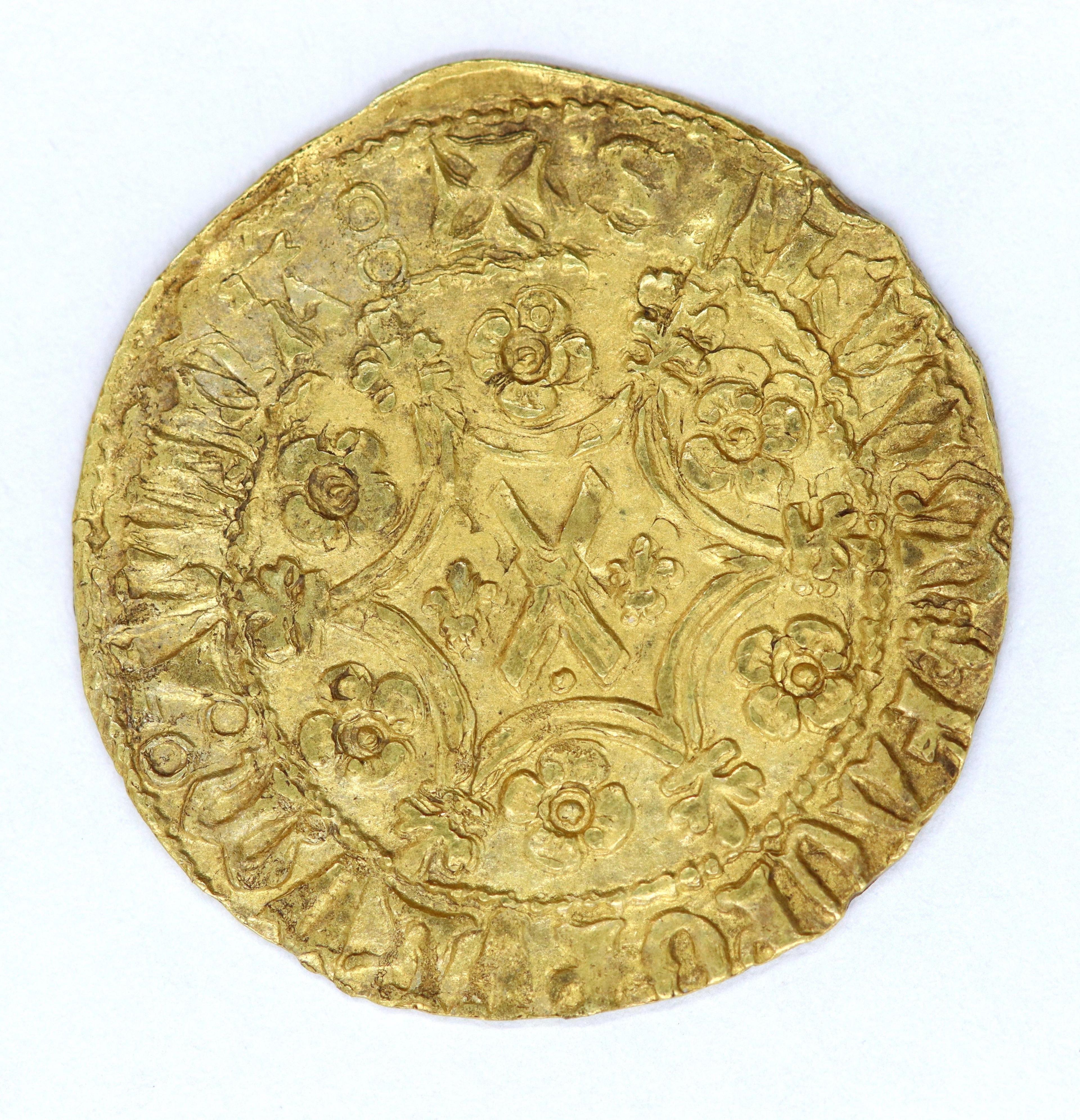 An old gold coin with an inscription round the outside and crosses and floral pattern in the middle