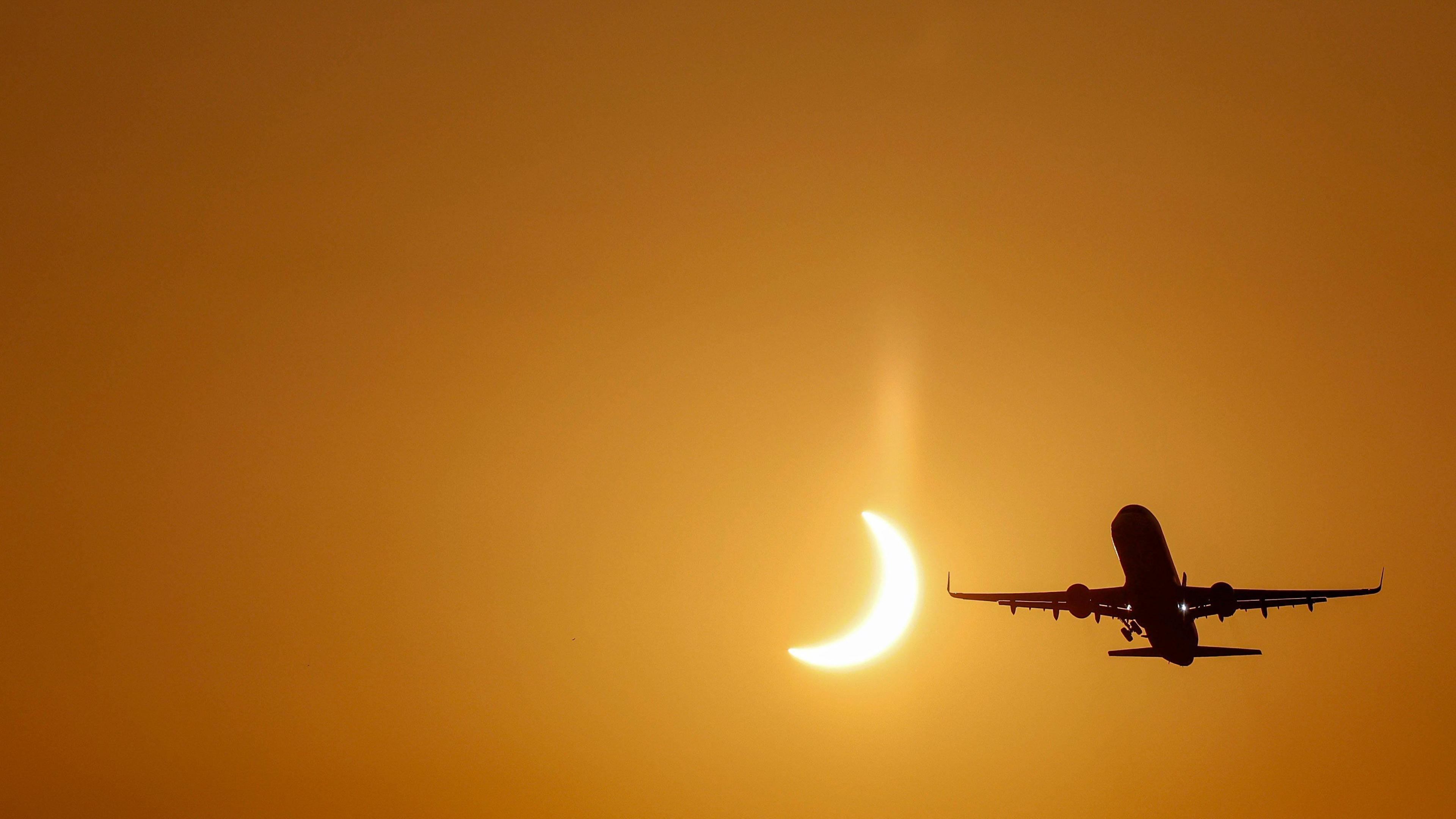 A plane flies past the Sun during the partial phase of a total solar eclipse over Valencia Airport in Spain.