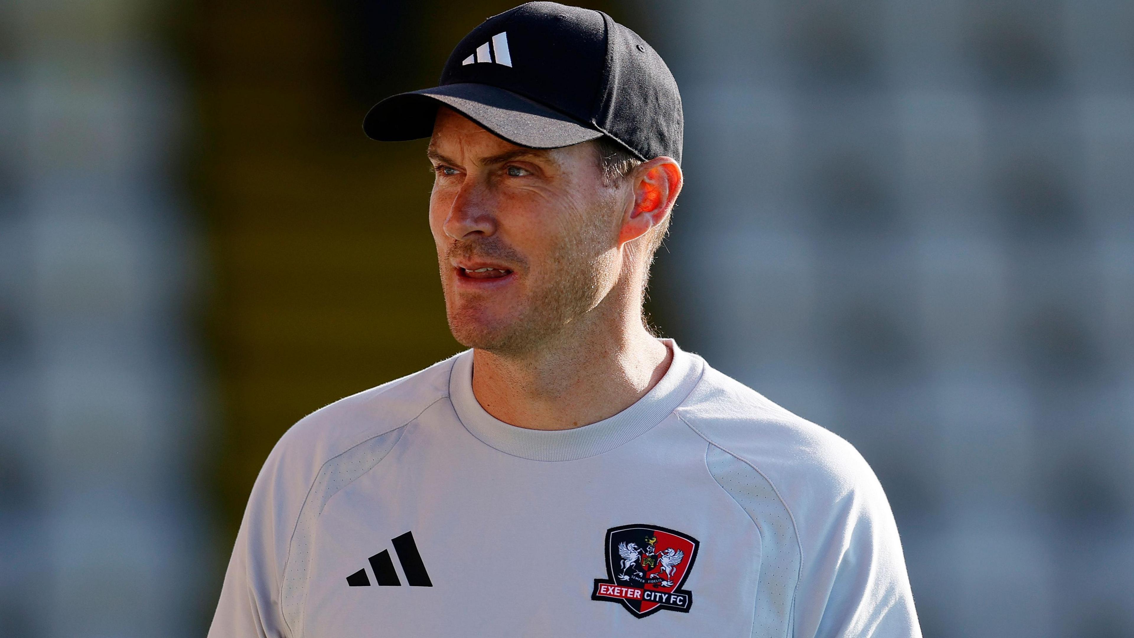 Matt Taylor wearing a black Adidas baseball cap and a light grey Exeter City training shirt with a black Adidas logo and the club badge on the front