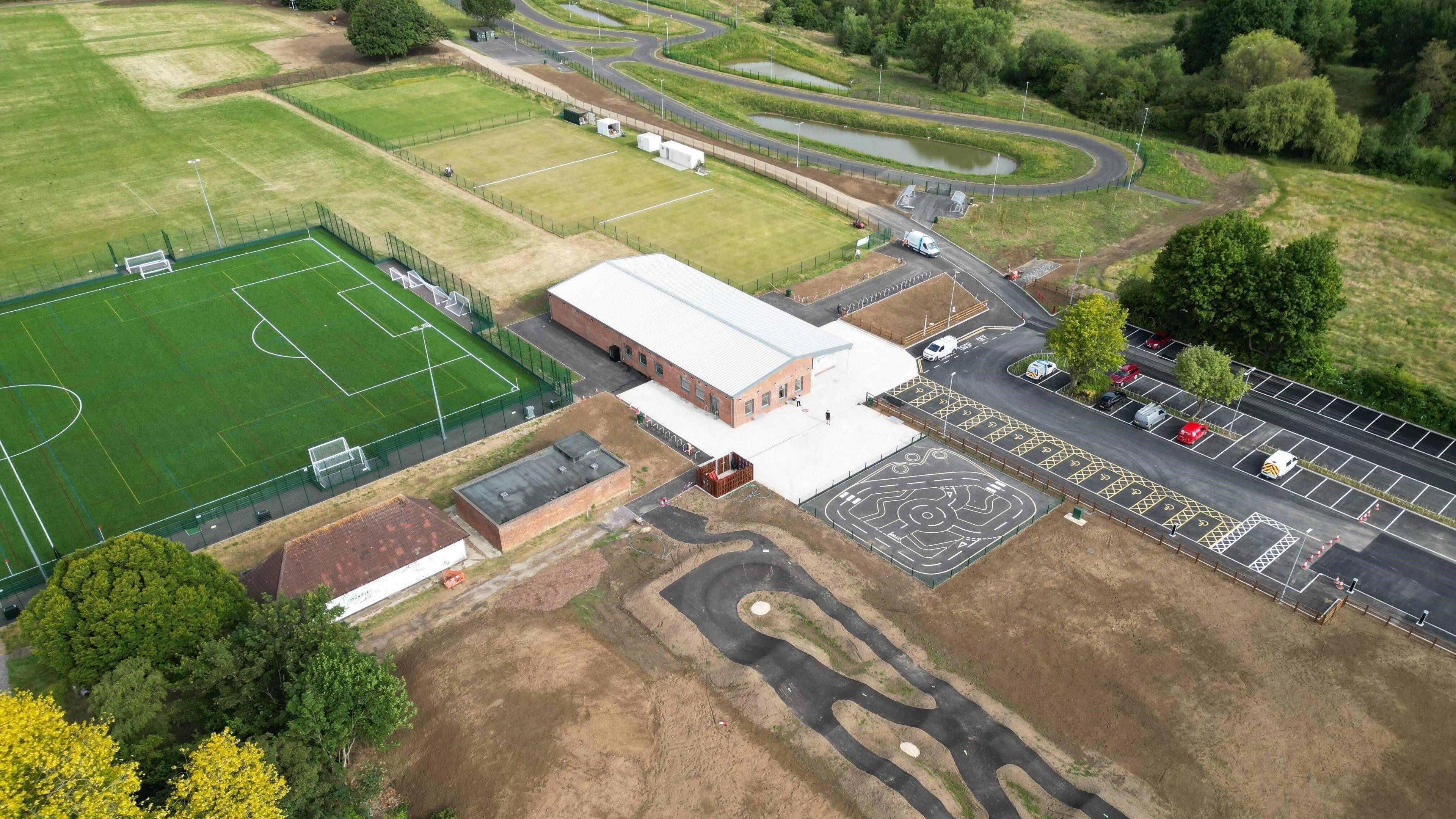 Overhead view of sports hub, with pitches, building, car park and cycling tracks