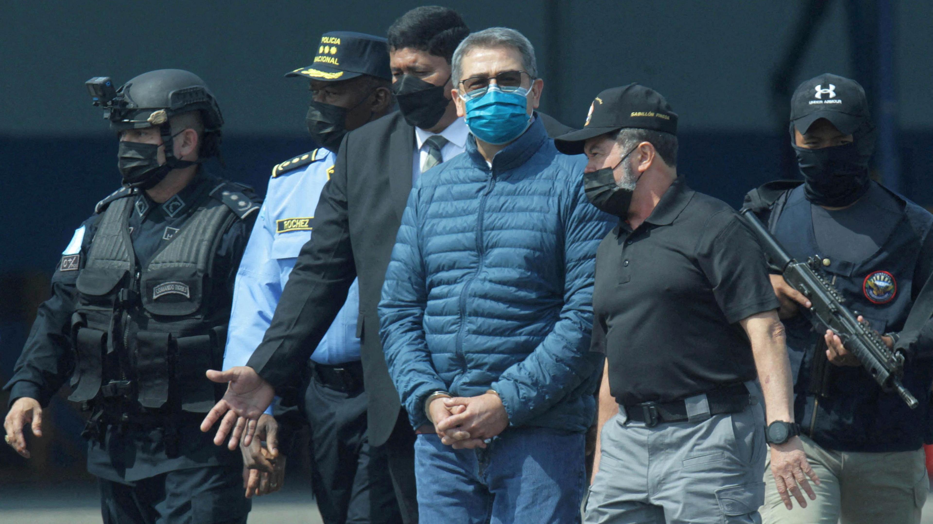 Honduras former President Juan Orlando Hernández is escorted by authorities as he walks towards a plane of the U.S. Drug Enforcement Administration (DEA) for his extradition to the United States, to face a trial on drug trafficking and arms possession charges, at the Hernan Acosta Mejia Air Force base in Tegucigalpa, Honduras, on 21 April 2022 