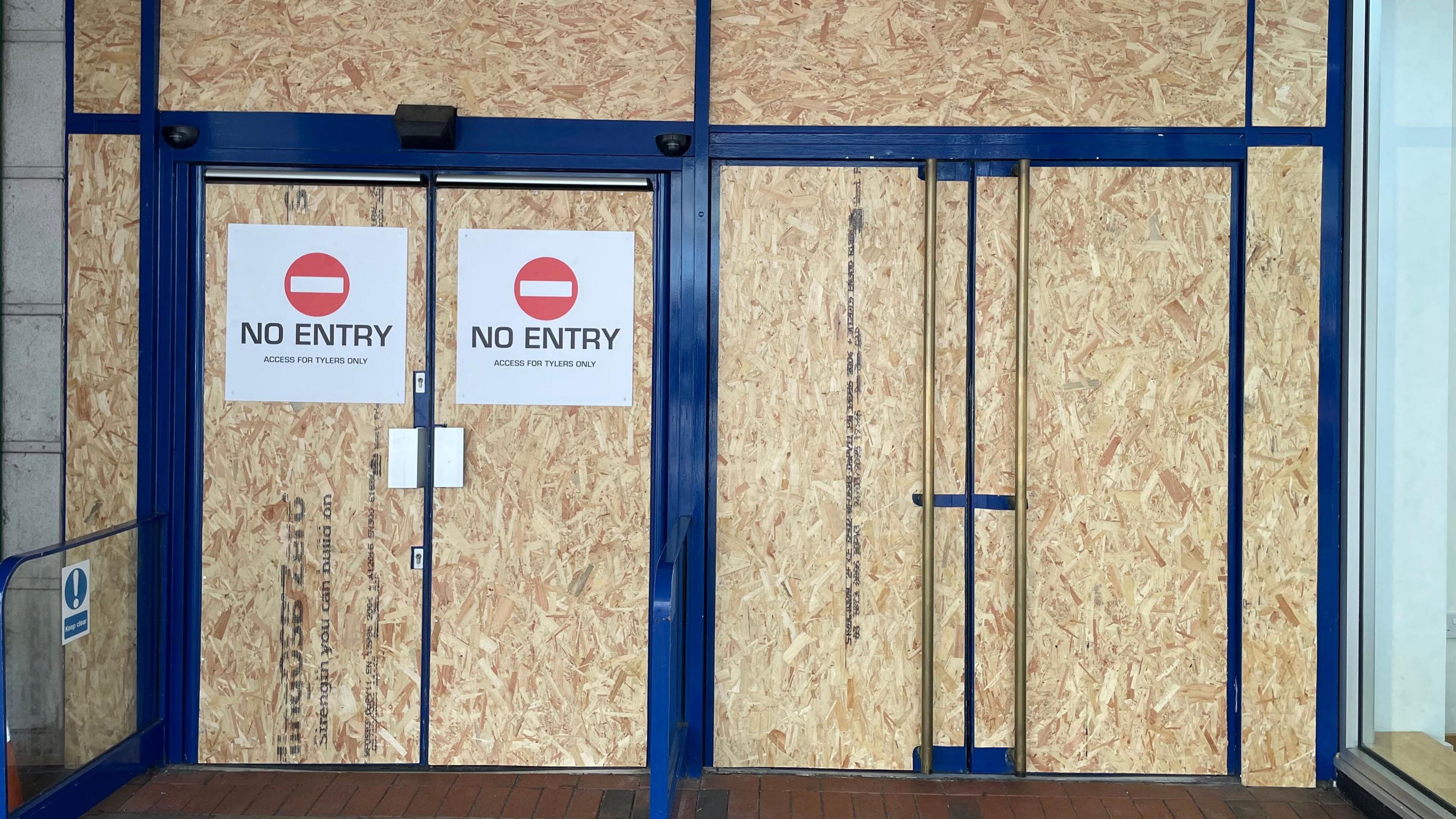 A doorway with boards on it and no entry signs.