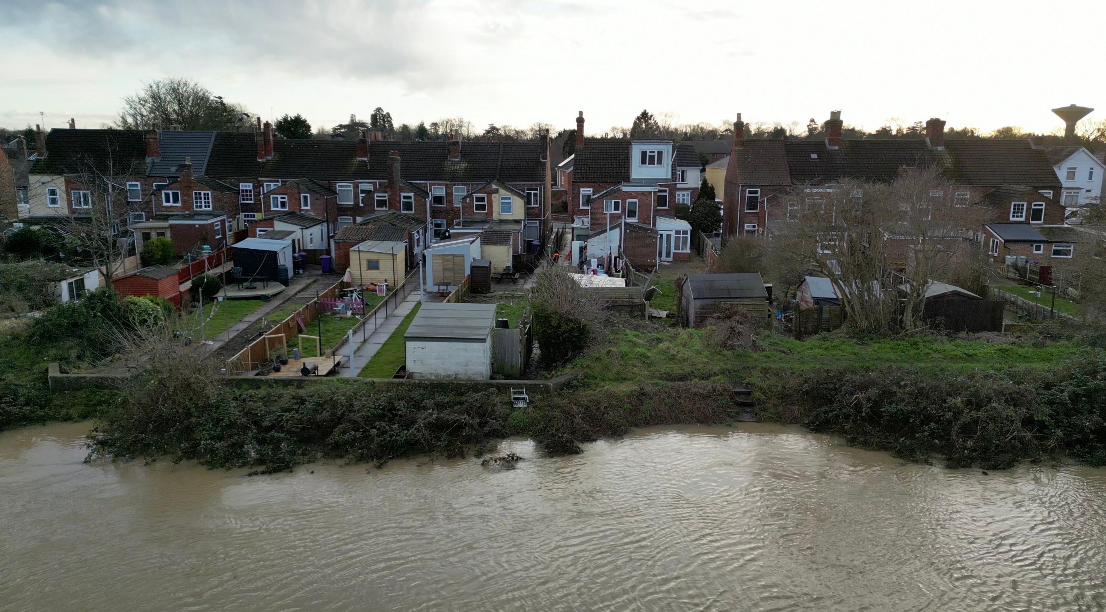 A drone image of the South Forty Foot Drain in Lincolnshire. The water way is in the foreground of the image and can be seen approaching the gardens of several properties which are on the banks.