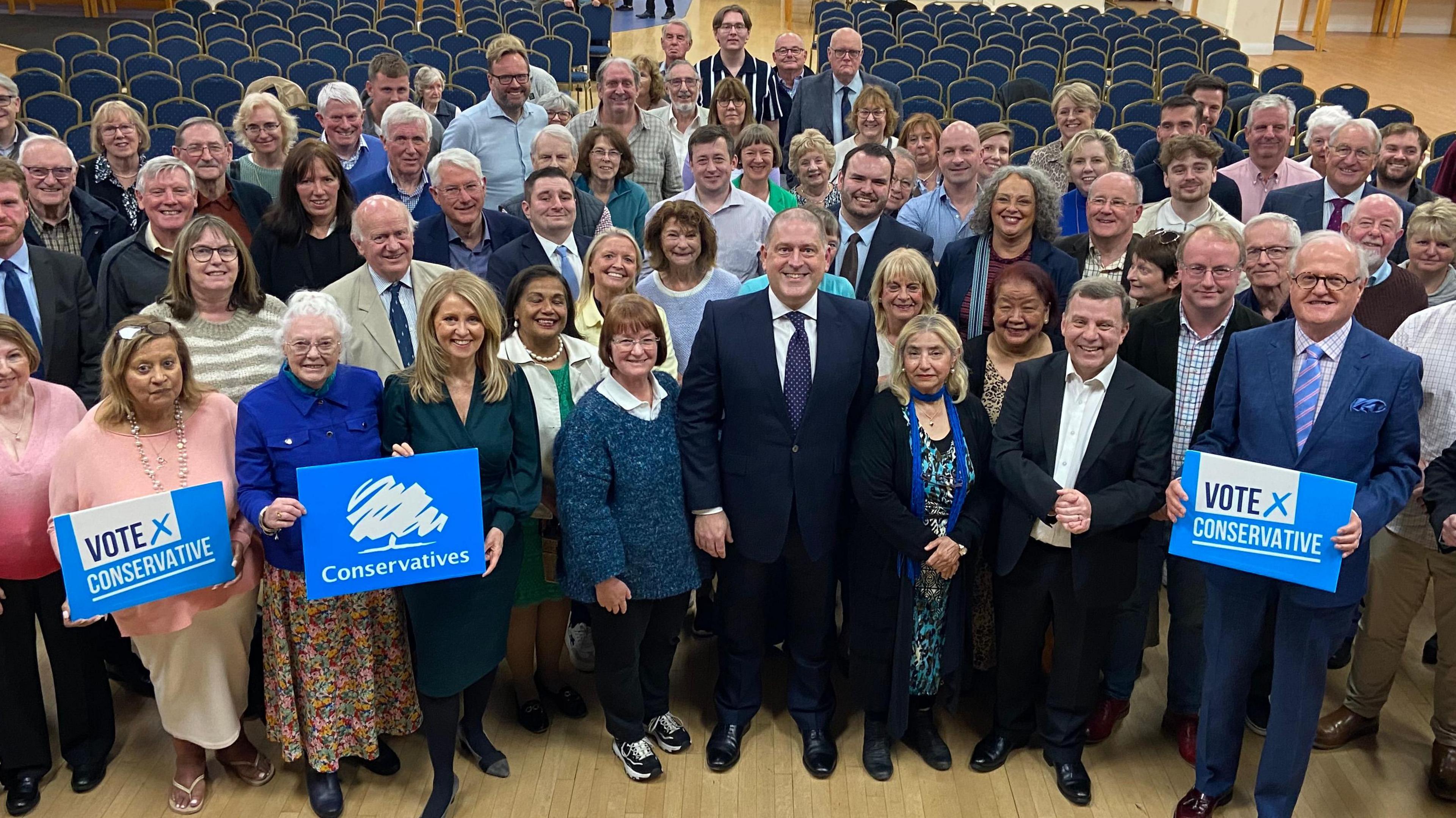 Ben Fletcher stands at the front and centre in front of Conservative party members. They include MP Esther McVey and former MP Andy Carter.