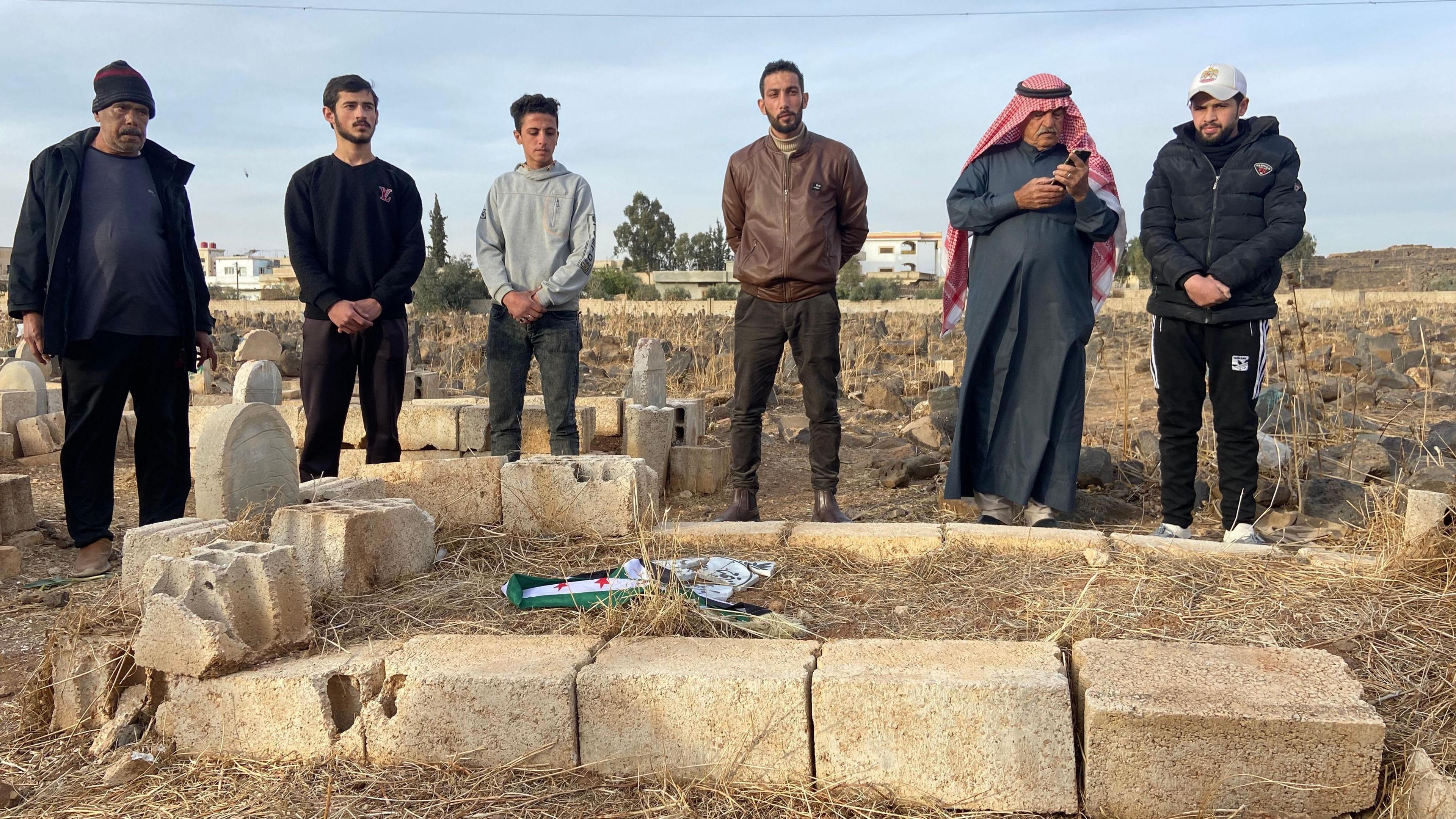 Neighbours watch in silence as the Syrian opposition flag was tied around Hamza's headstone.