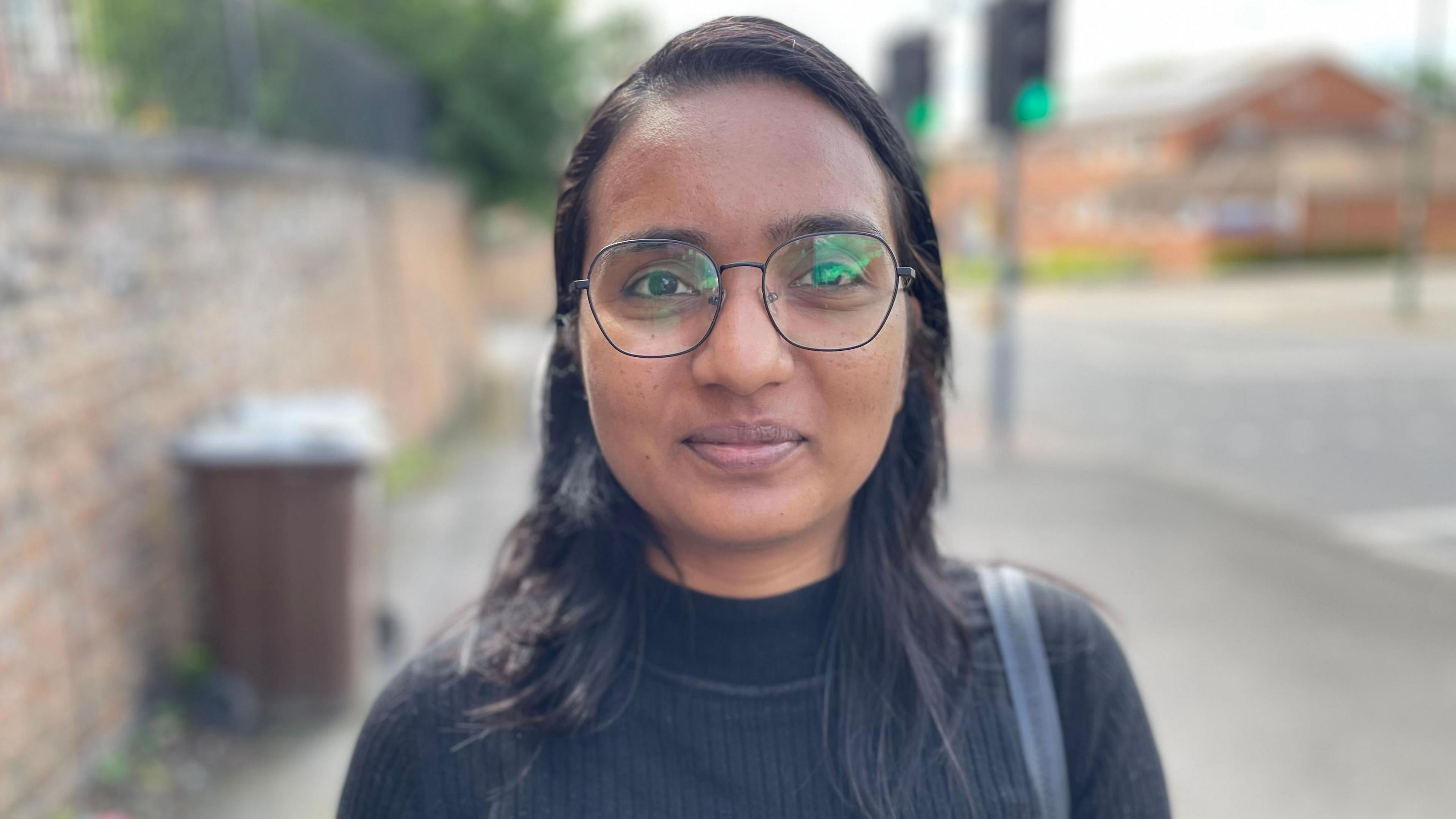 Himanshi is wearing a black top and glasses