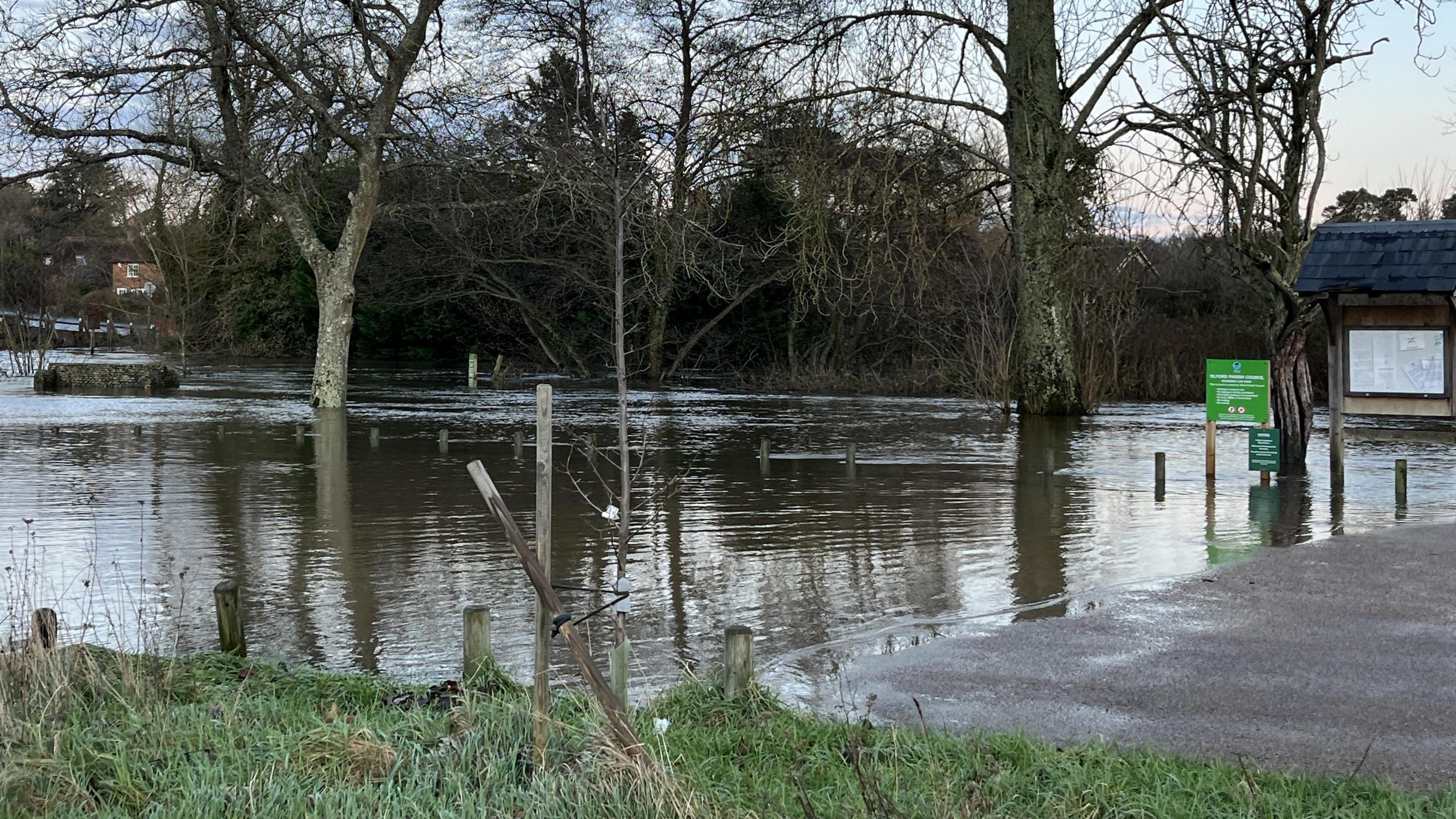 A river seeps onto a pathway and grassy verge.