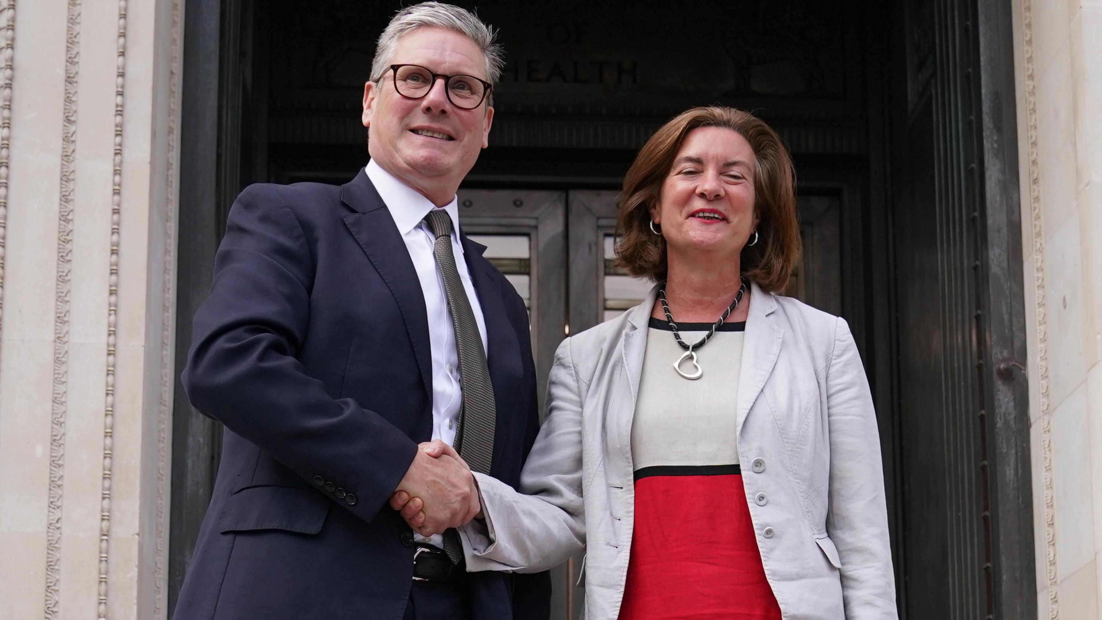 Sir Keir Starmer and Eluned Morgan smiling and shaking hands on the steps of the Welsh government headquarters in Cathays Park, Cardiff