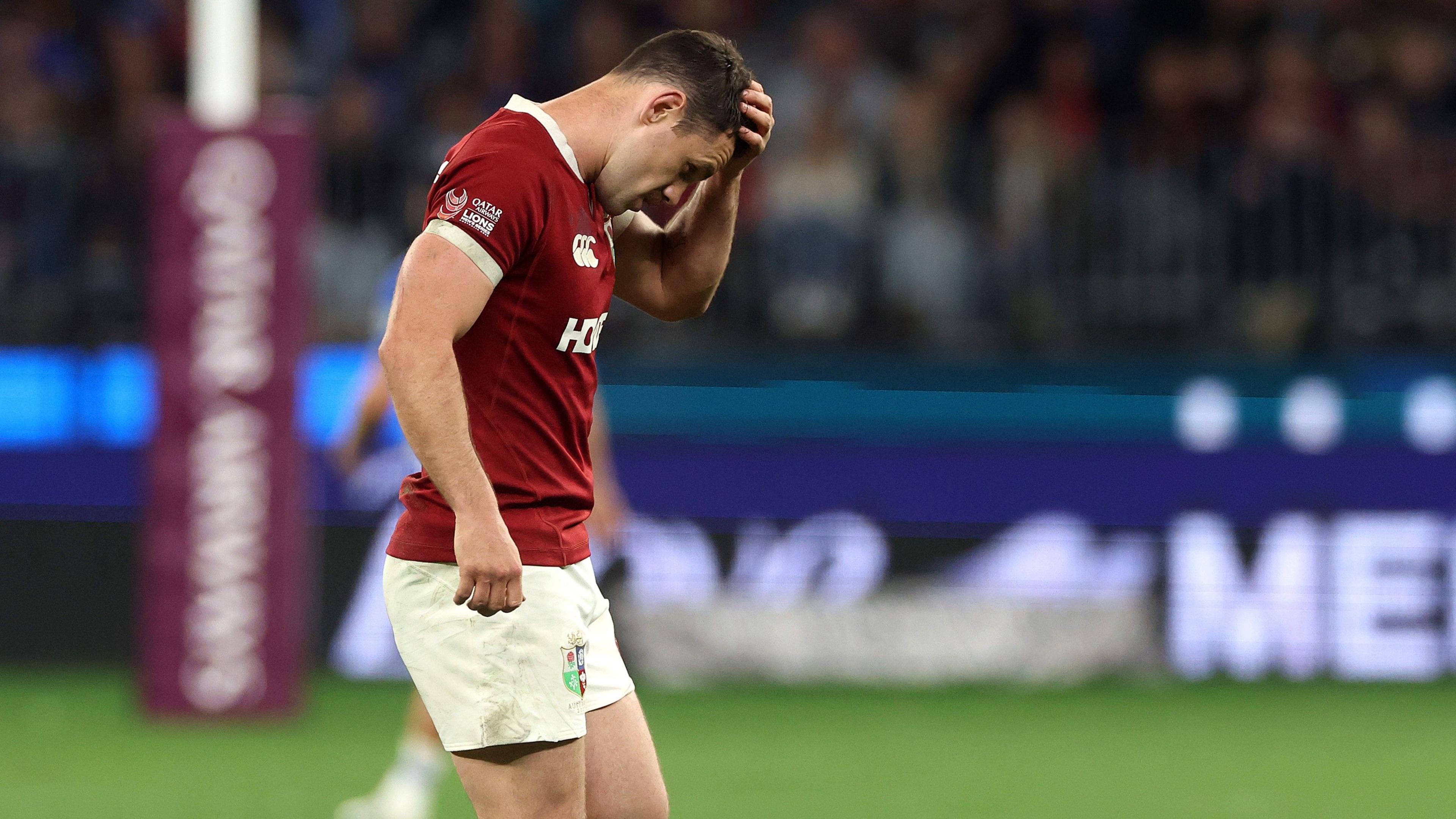 Tomos Williams holds his head and looks dejected as he walks off the pitch