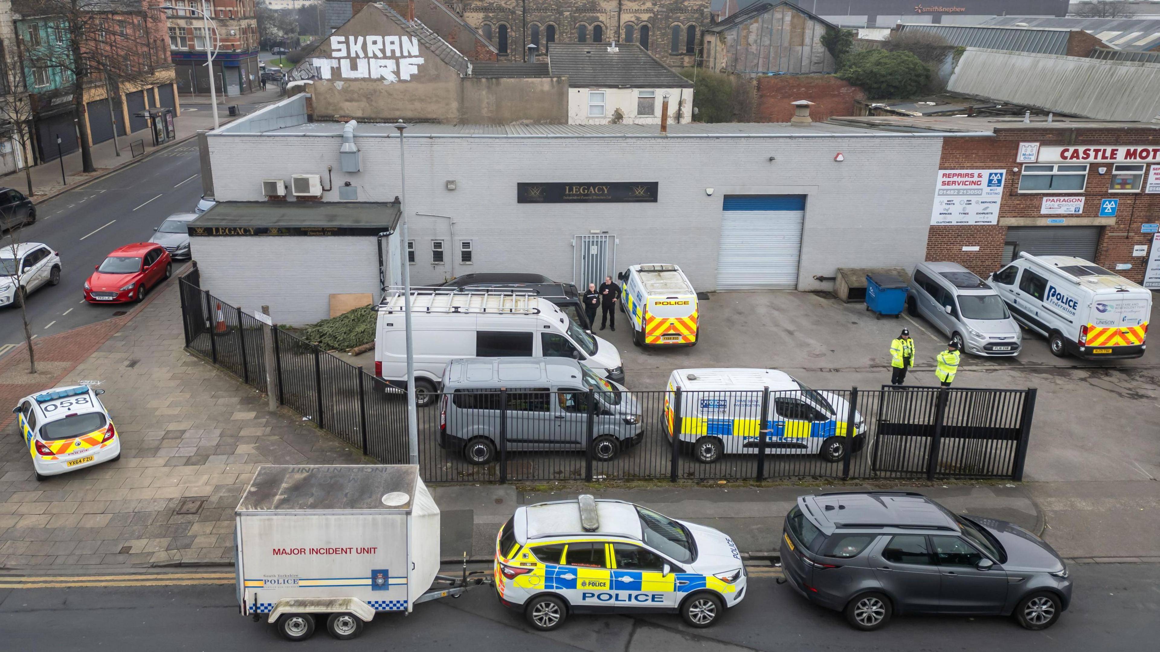 A drone picture showing a number of police vehicles, including one towing a "Major Incident Unit" trailer, outside the premises of Legacy Independent Funeral Directors in Hull