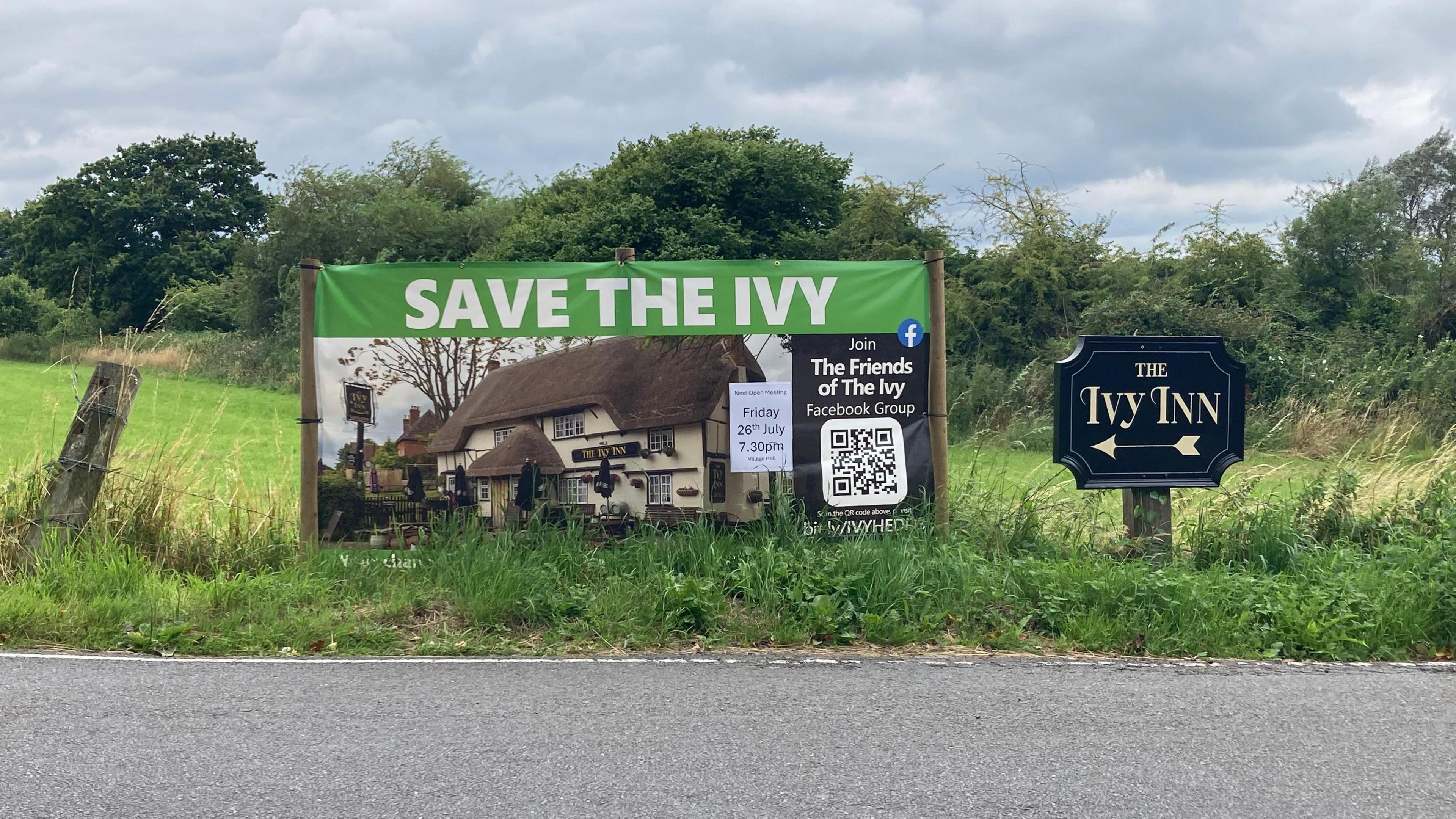 A roadside sign saying save the ivy road, next to a sign pointing visitors to the ivy inn