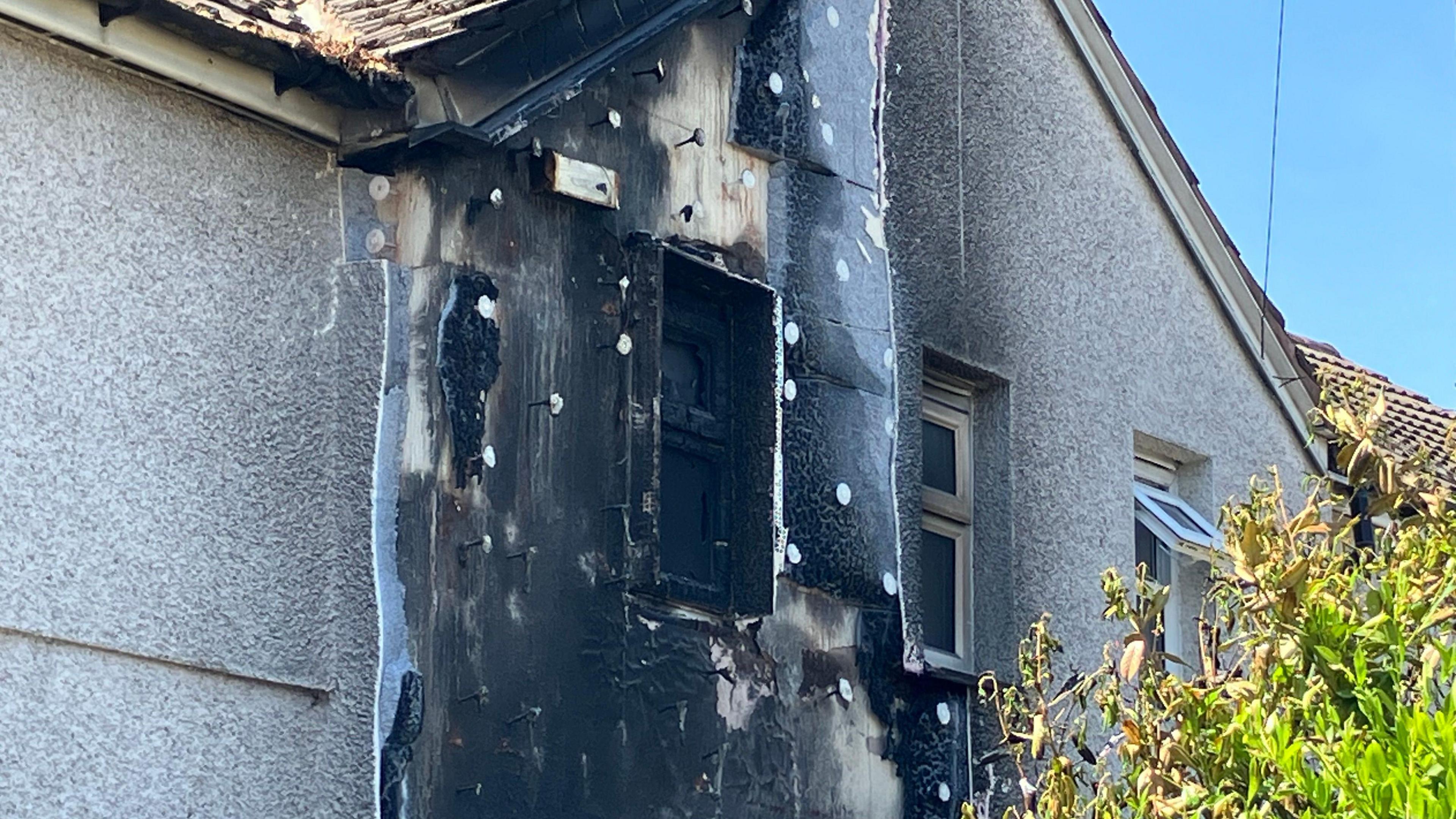 A close up of the first floor window of a two-storey house damaged by fire