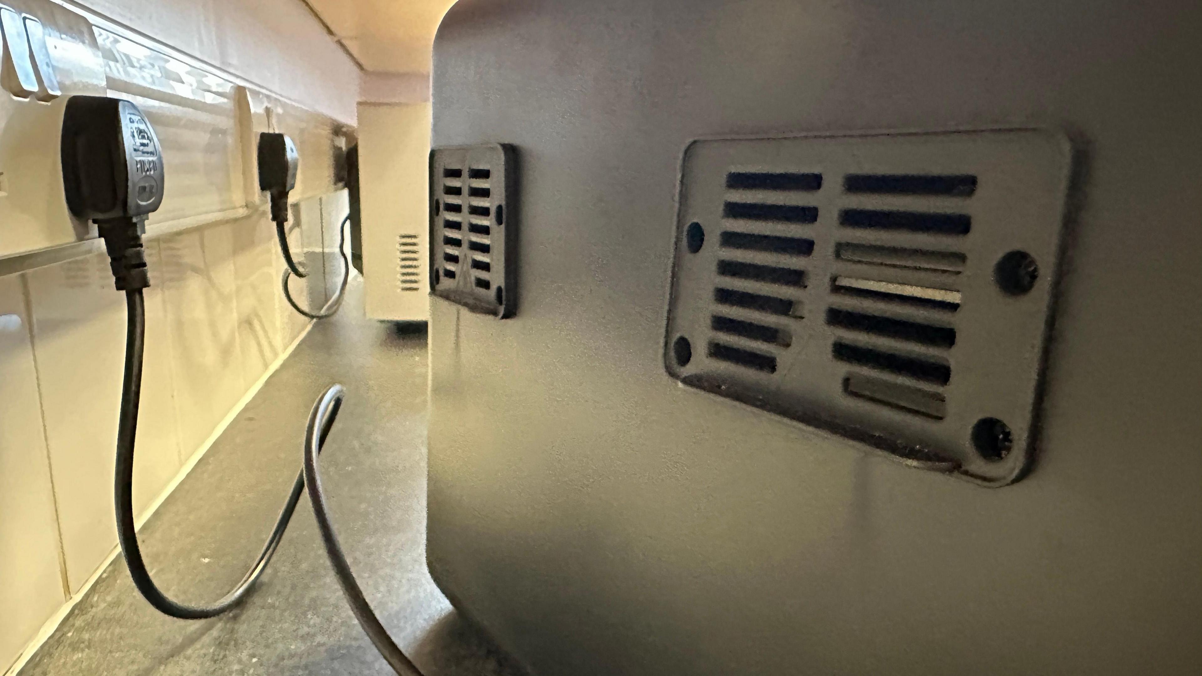 The back of an air fryer plugged in on a kitchen worktop.