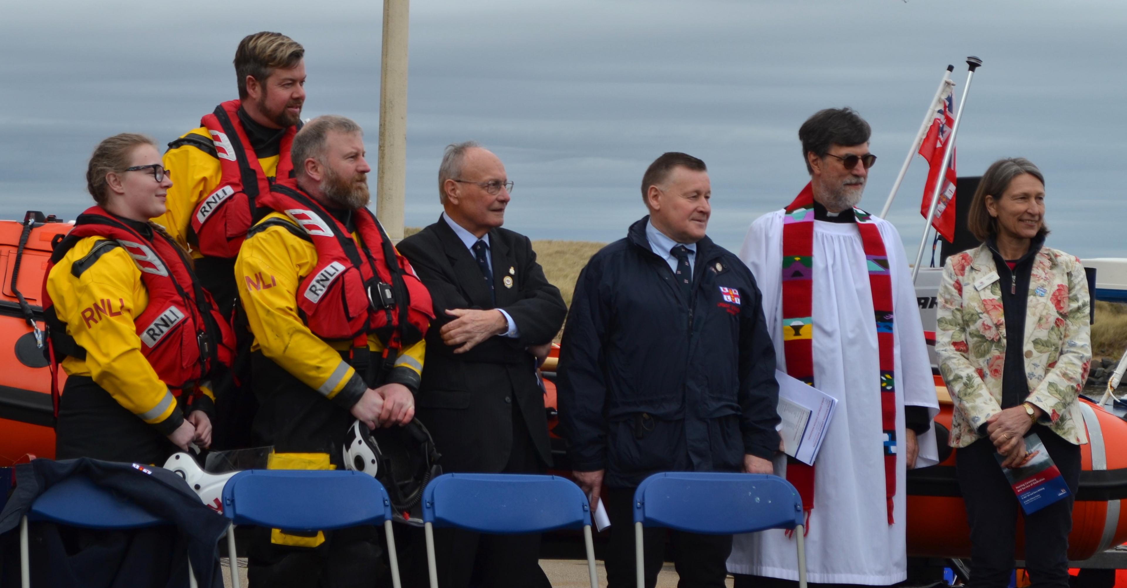 Volunteers and RNLI staff stand and watch