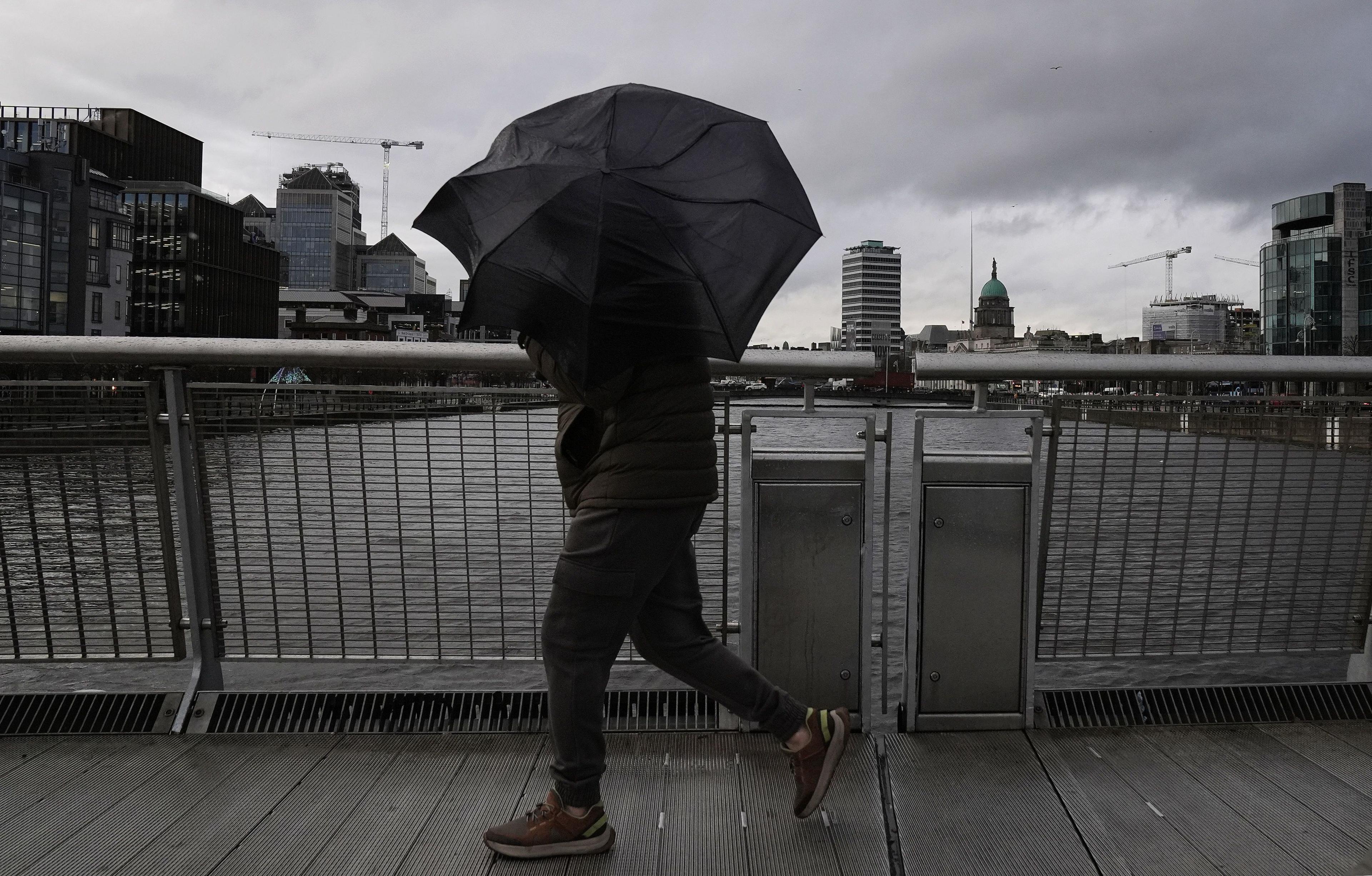 A person struggles with their umbrella as the wind picks up in Dublin's city centre. Storm Darragh is approaching the UK and Ireland.