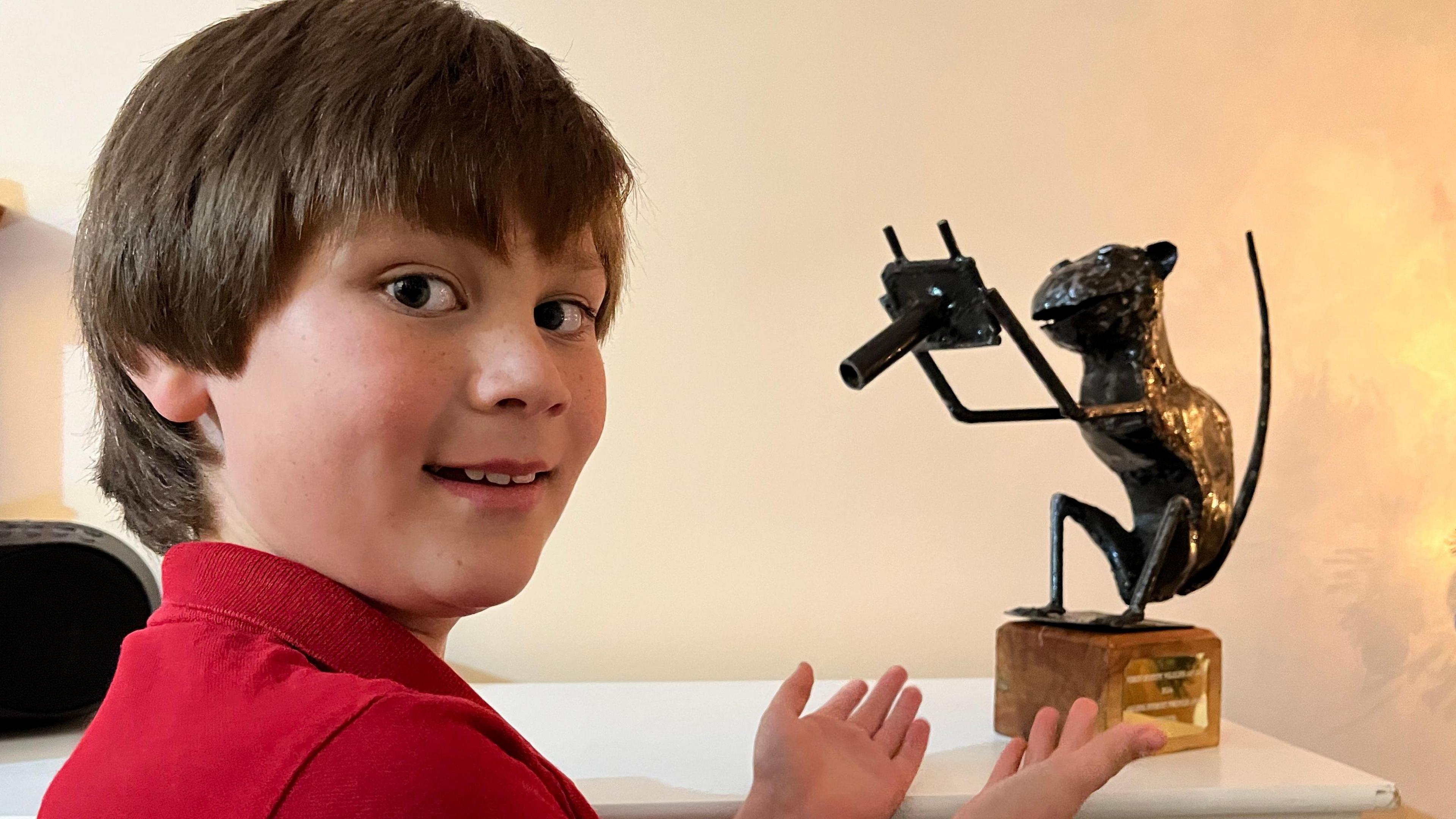 Flynn with his photography award which is made out of metal in the shape of a monkey holding a camera stood on a block of wood with a shiny plaque on the side