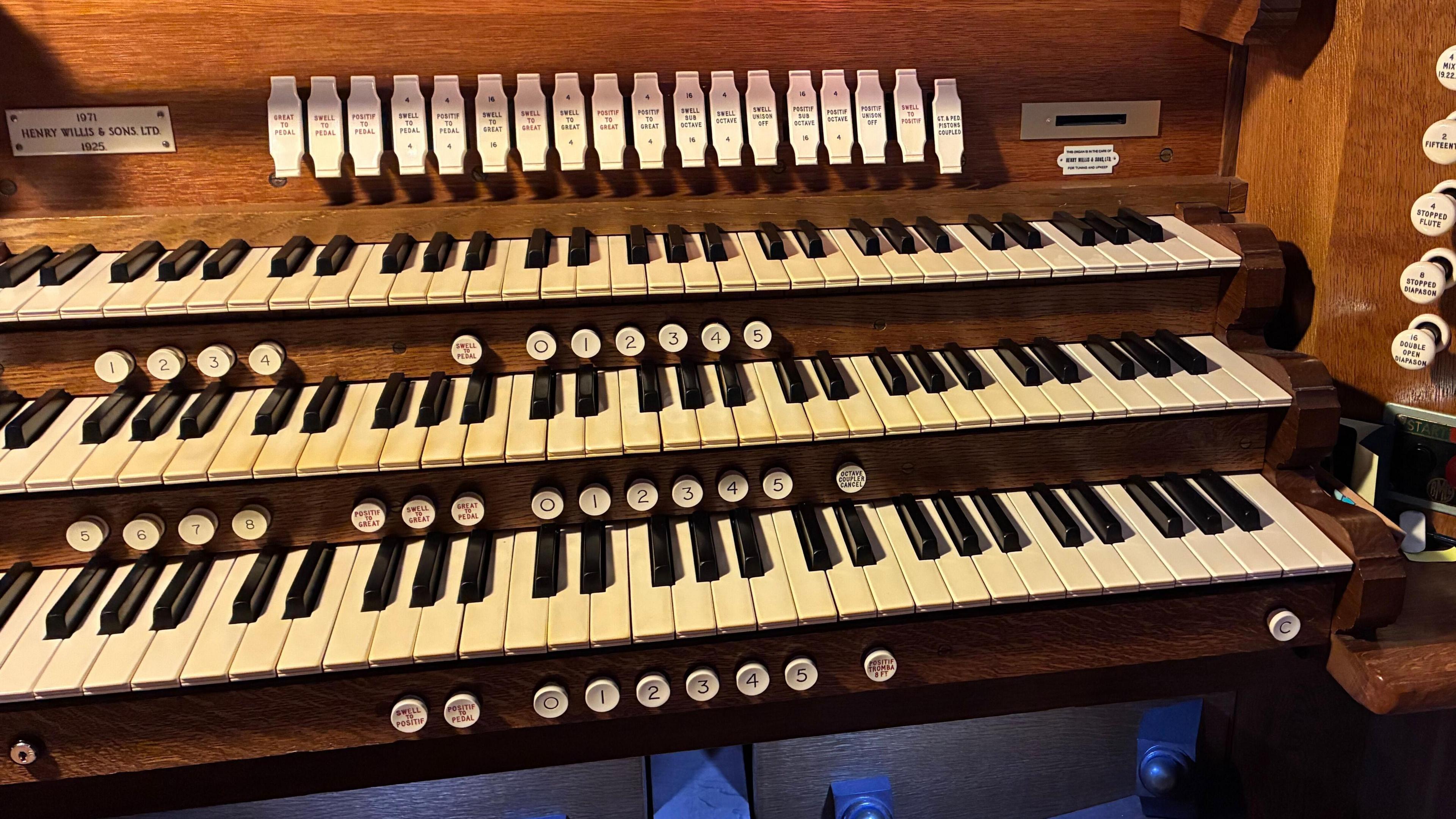 Sitting detached from the organ pipes and next to some church pews is the keyboard of the instrument.