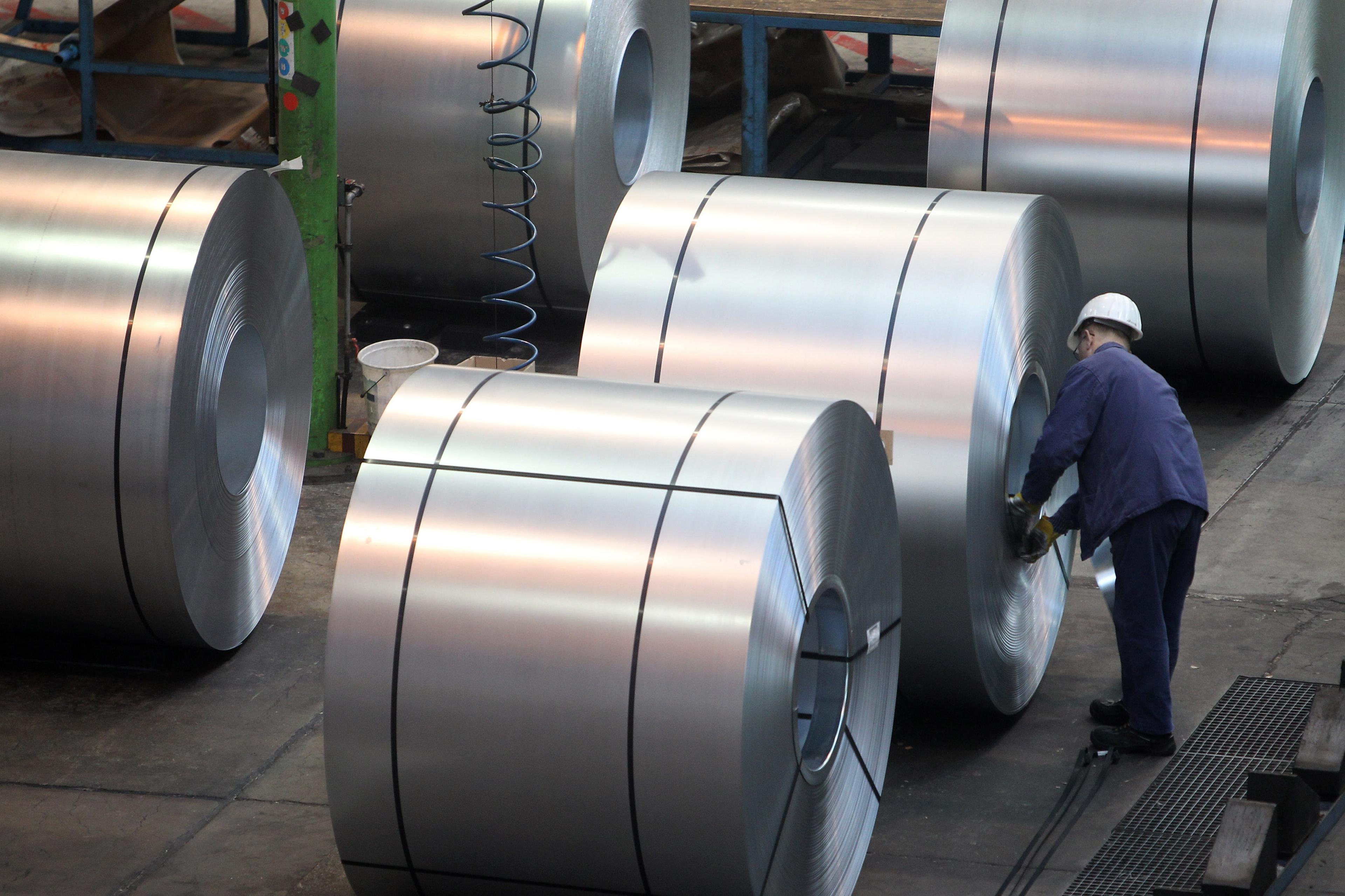 A worker inspects steel in a factory