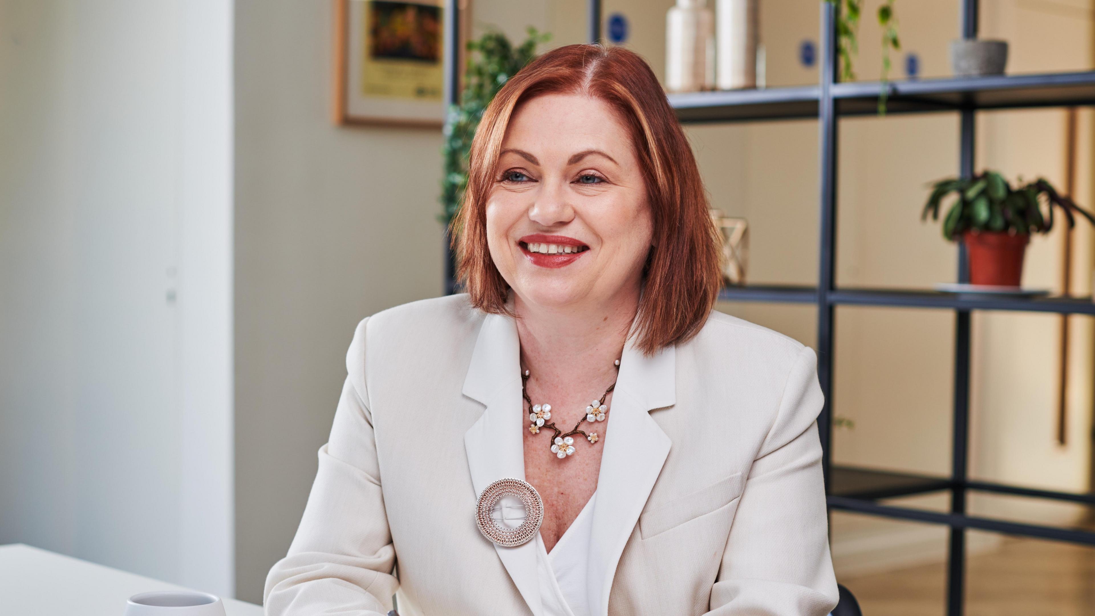 Dr. Lynne Guyton, is CEO of John Lyon’s Charity. She is sitting at a desk writing.