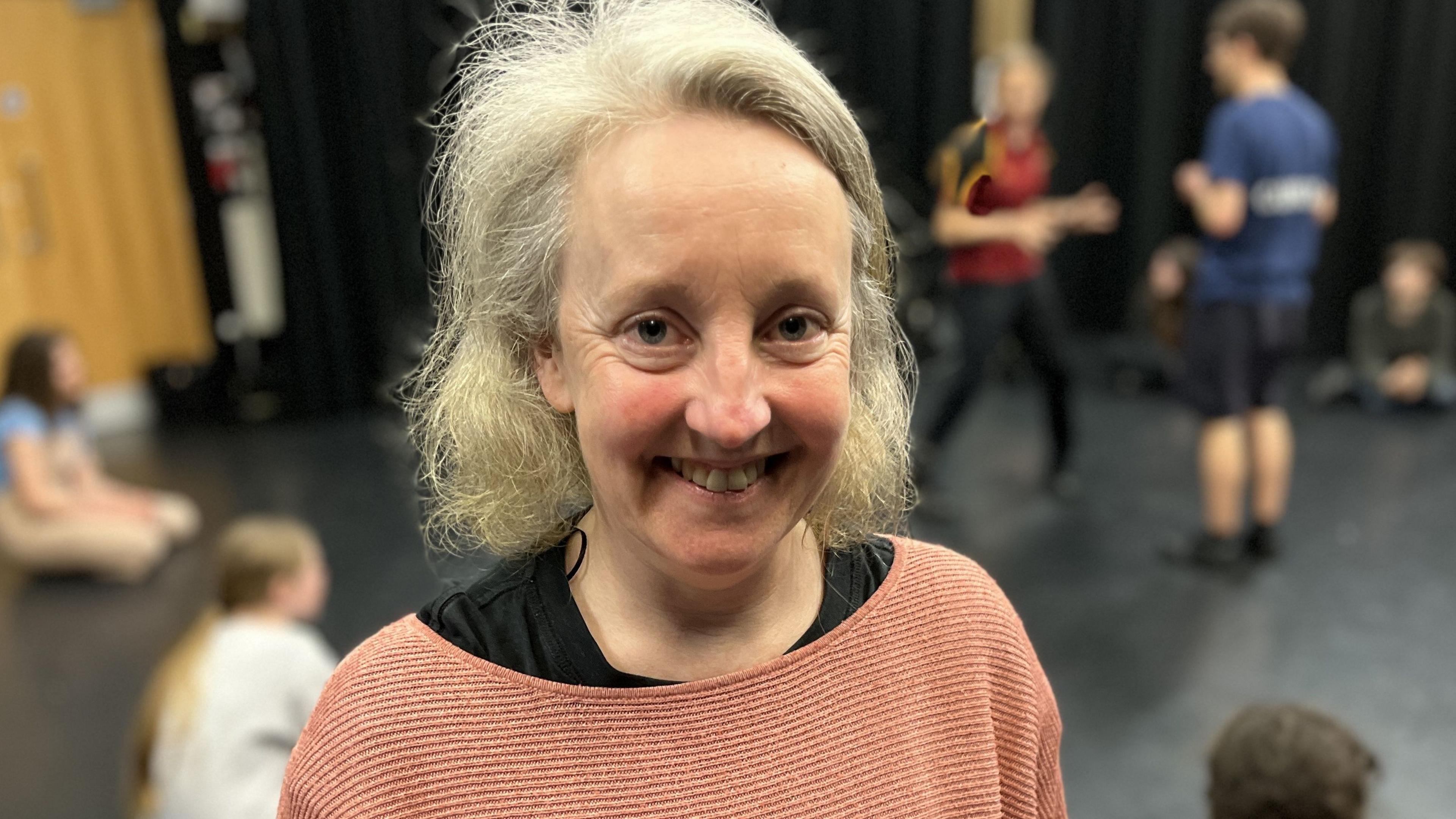 Tessa Slack standing in front of teenagers taking part in the workshop, smiling with shoulder length grey, curly hair