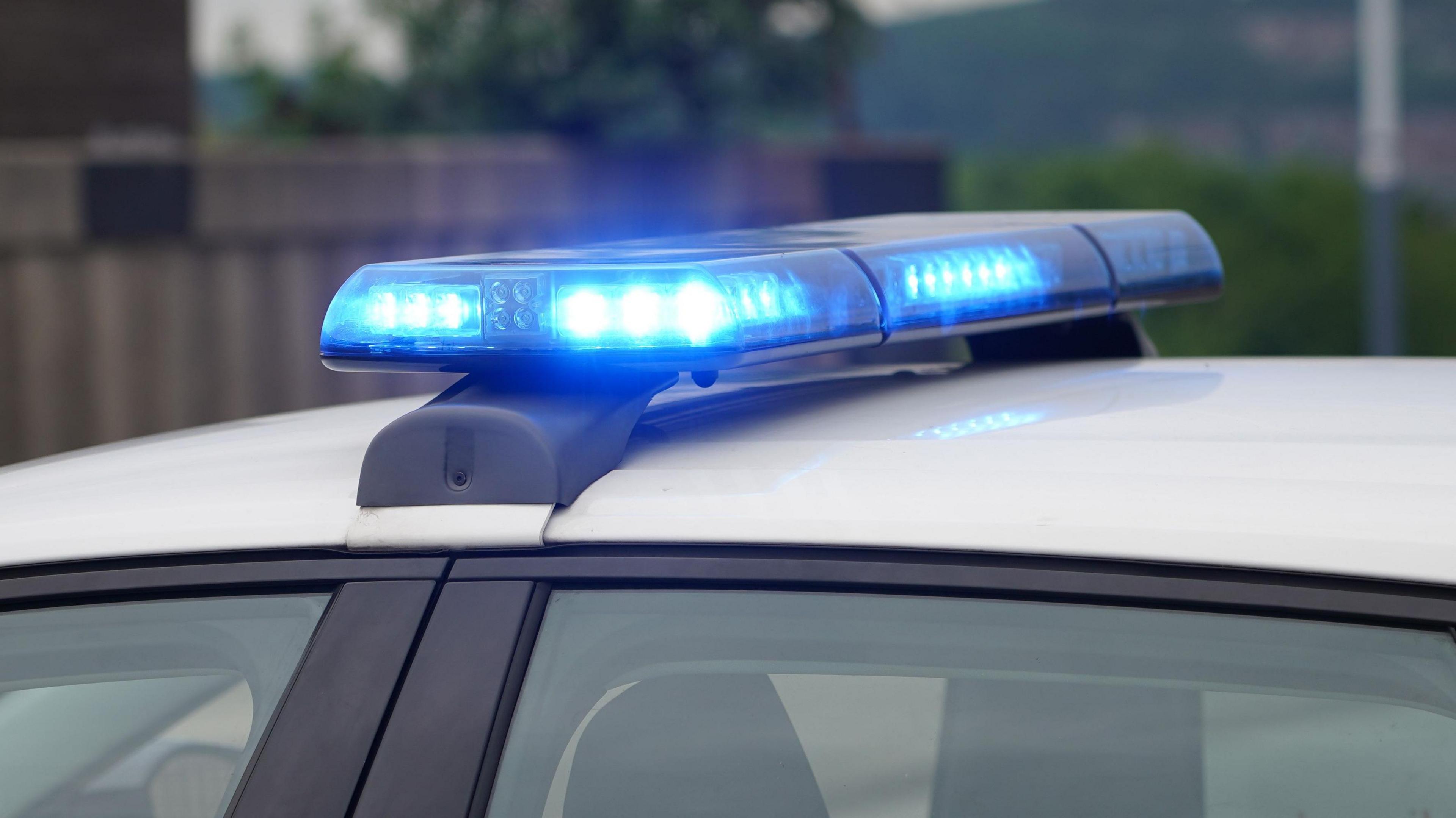 Roof of white police car with blue lights flashing