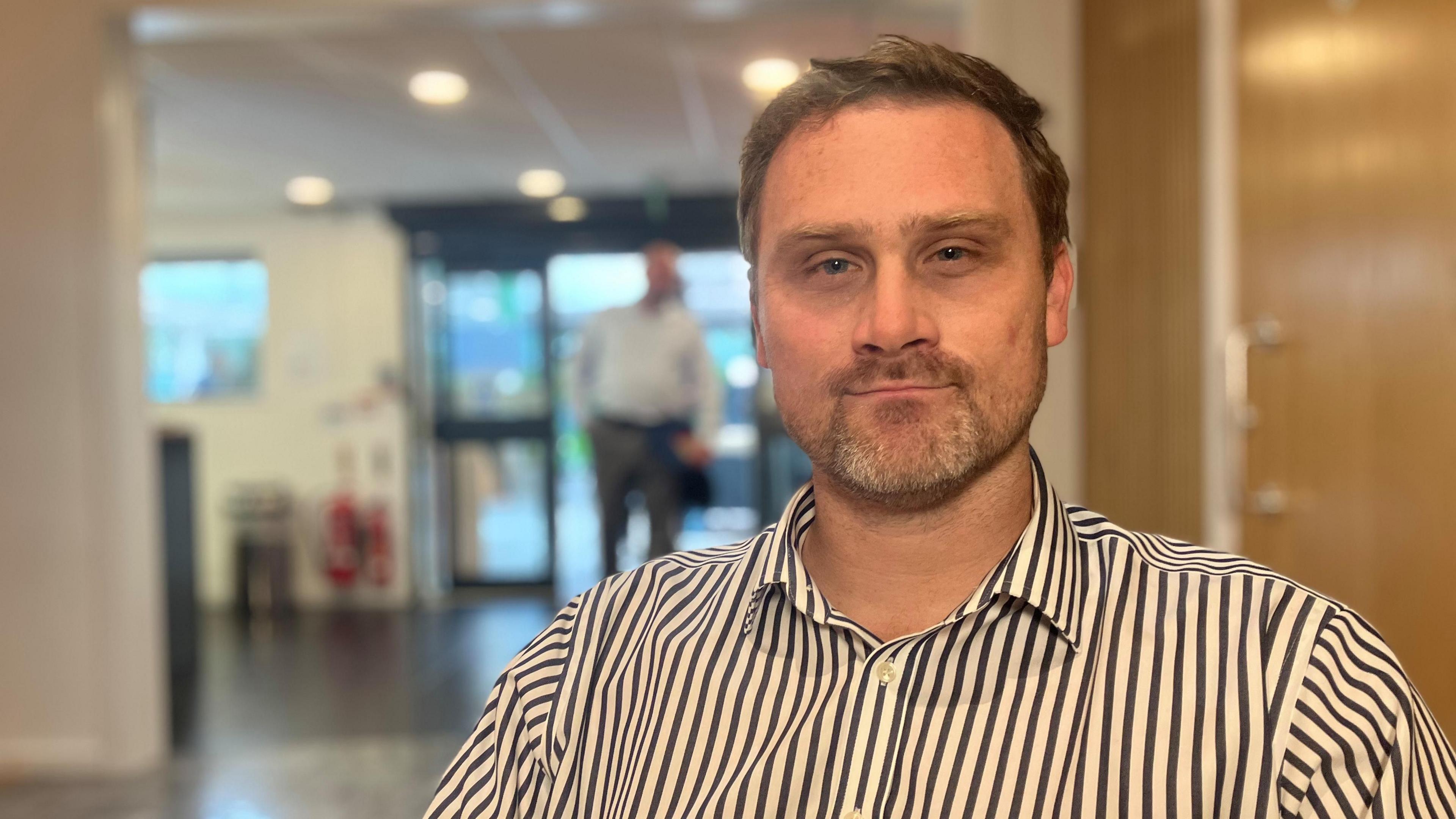 a man in a black and white stripey shirt sitting in the foyer of a conference centre