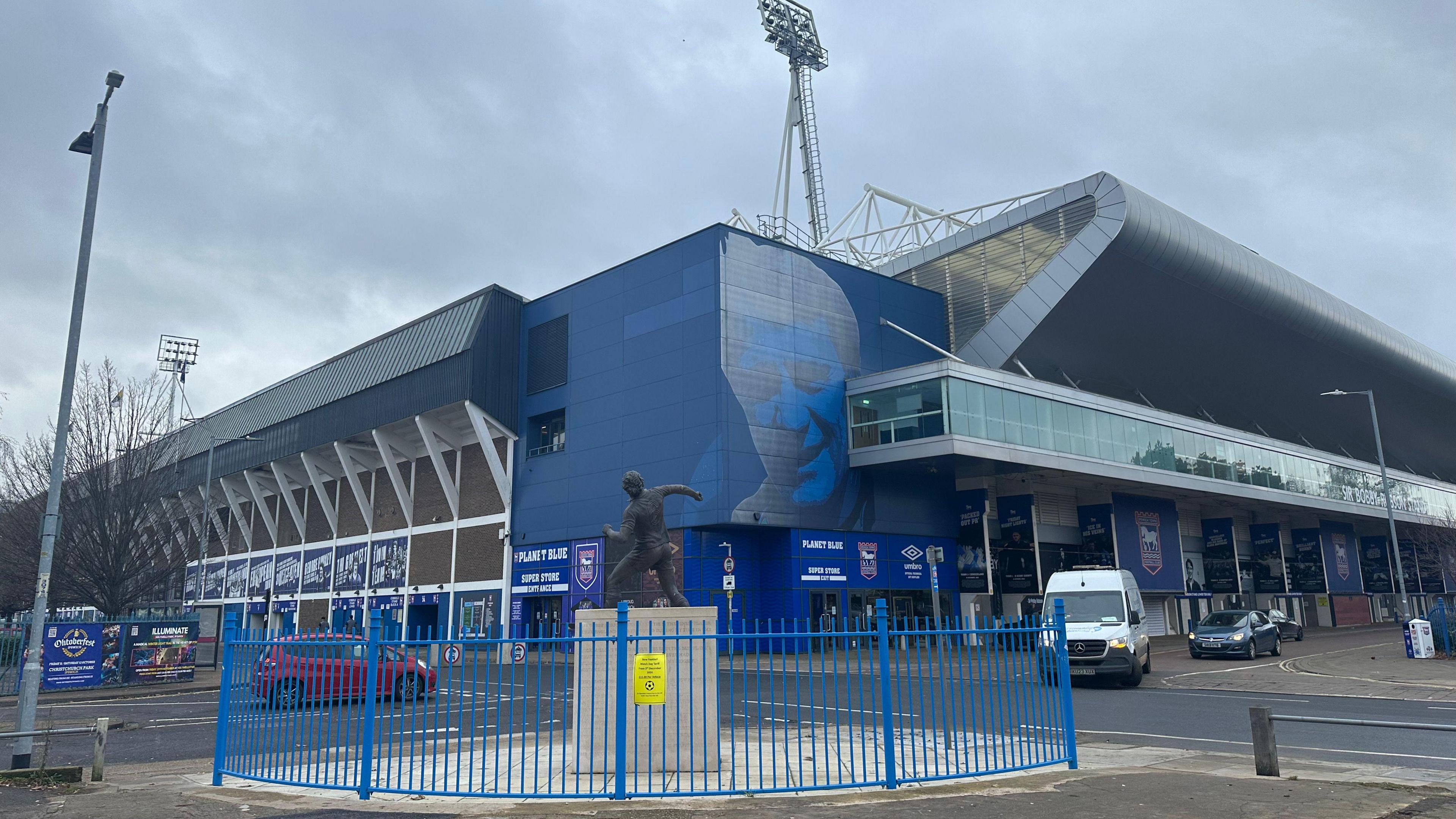 A general view of the outside of Portman Road stadium. Vehicles pass on the roads directly outside the stadium. 