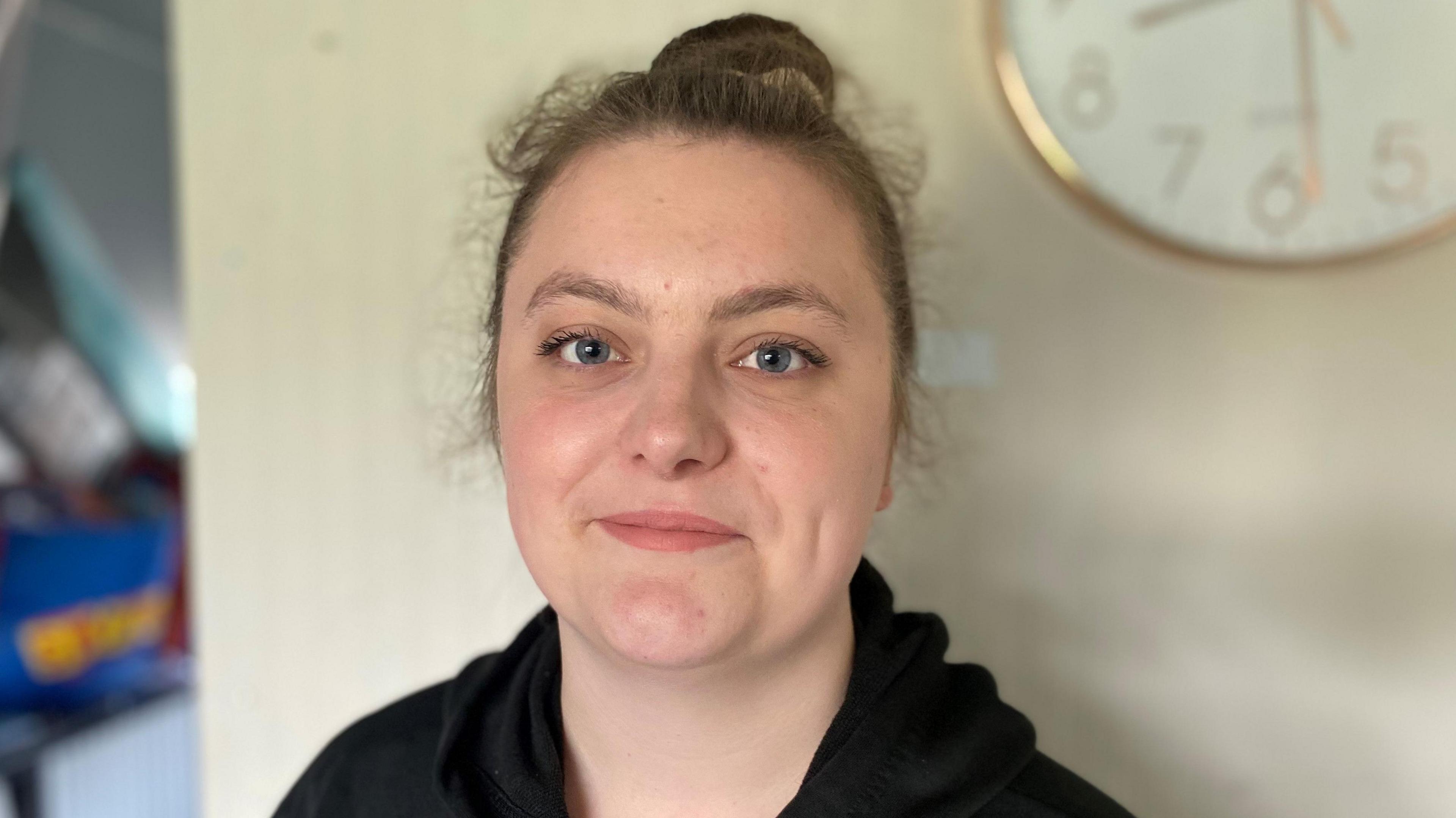 Chloe Ramsden looks at the camera. She has brown hair tied up in a bun and is wearing a black jumper.