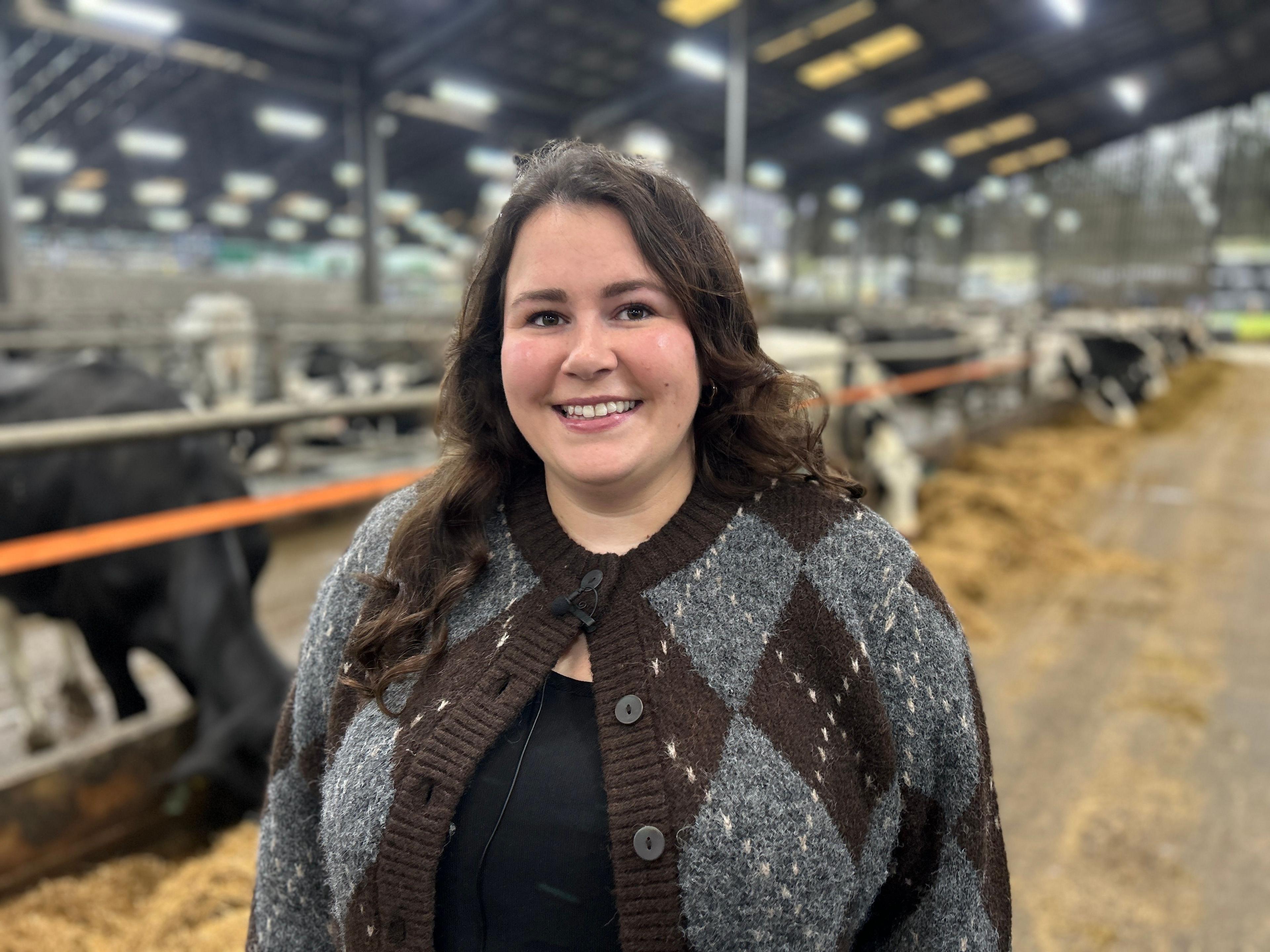 Dr Holly Ferguson wearing a knitted cardigan and standing inside the dairy shed at the Barony Campus