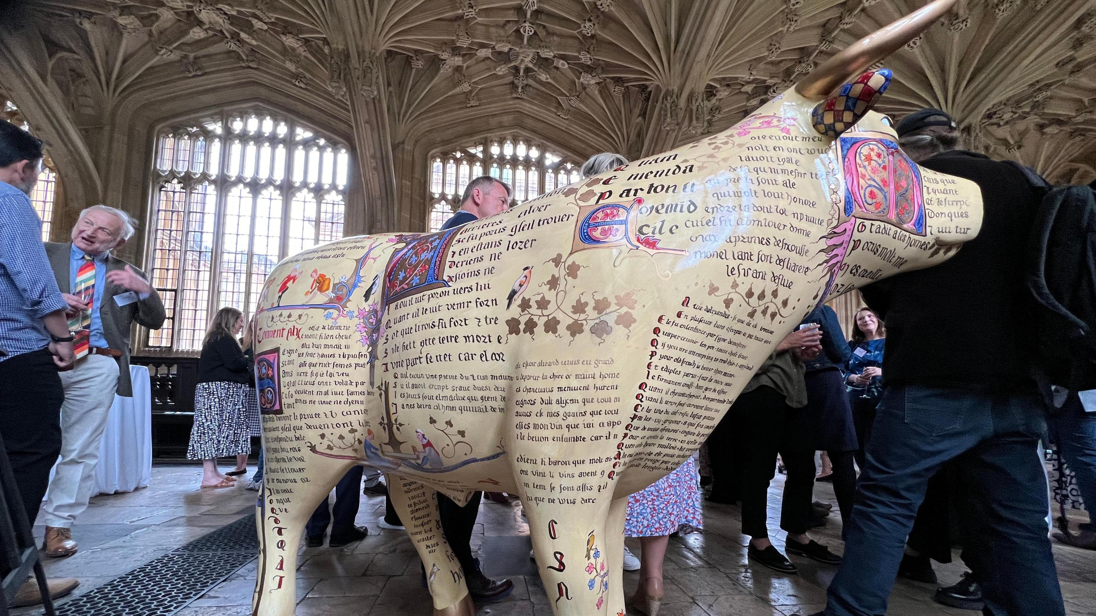 A large sculpture of the ox on display with people walking around it.